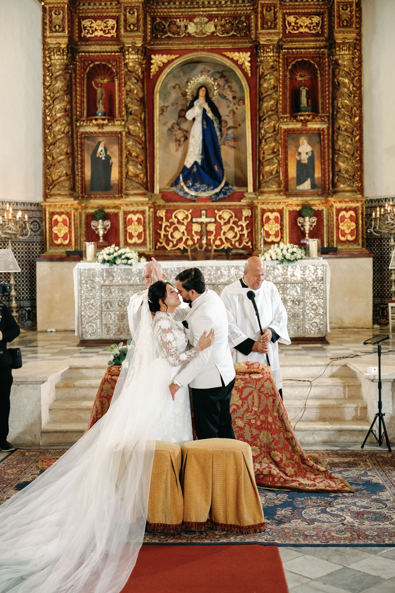 Traditional church wedding ceremony with elegant decorations and gilded religious artwork on display.
