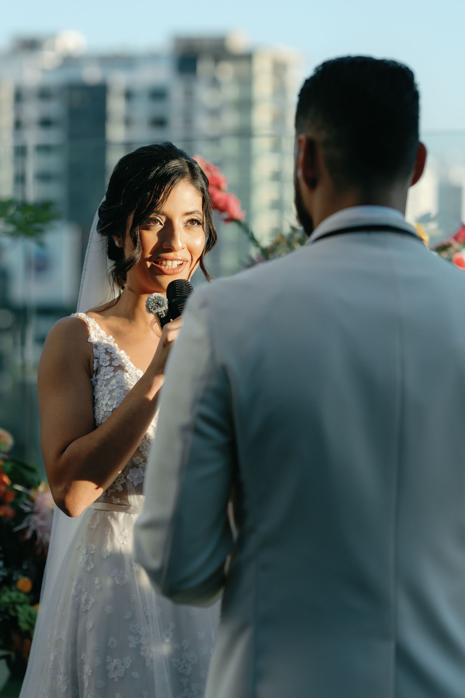 A couple shares an intimate moment during their outdoor wedding ceremony with city buildings in the background.