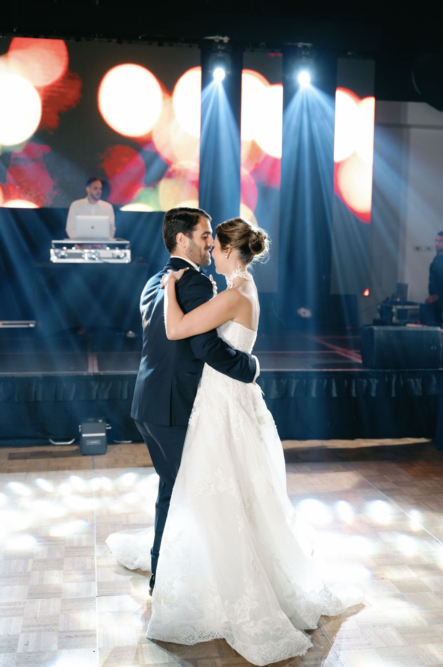 Romantic first dance sequence of newlyweds on illuminated dance floor with red and blue lighting effects.