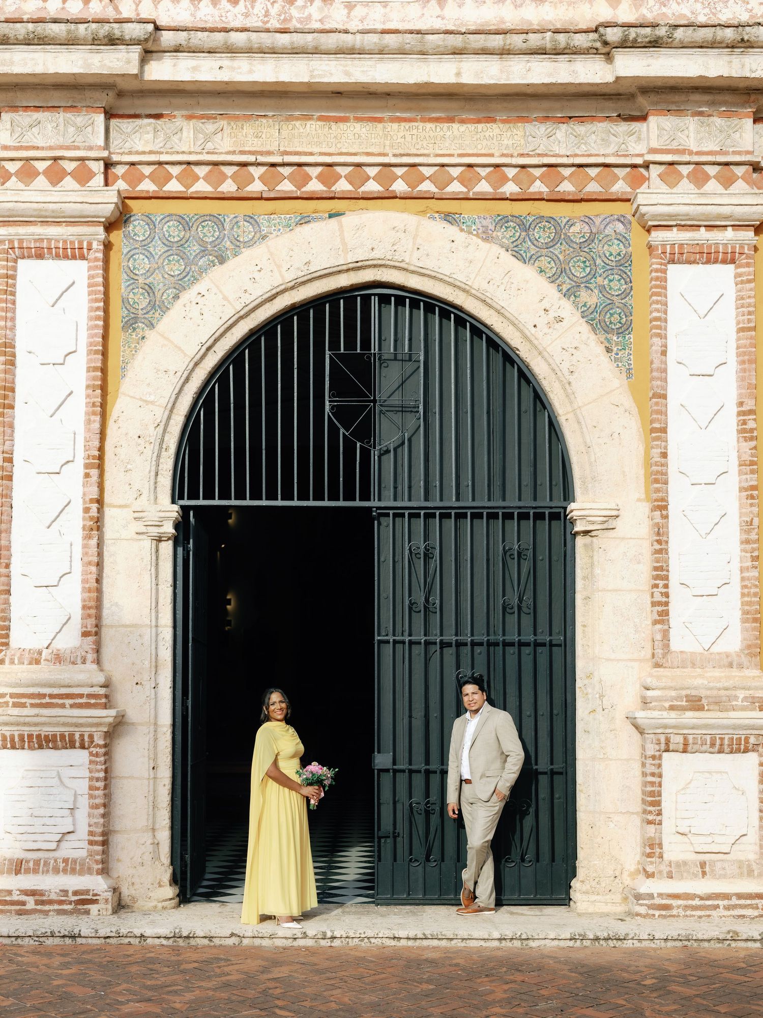 Four connected archways with decorative tiles and iron gates show the architectural details of a historic building entrance.