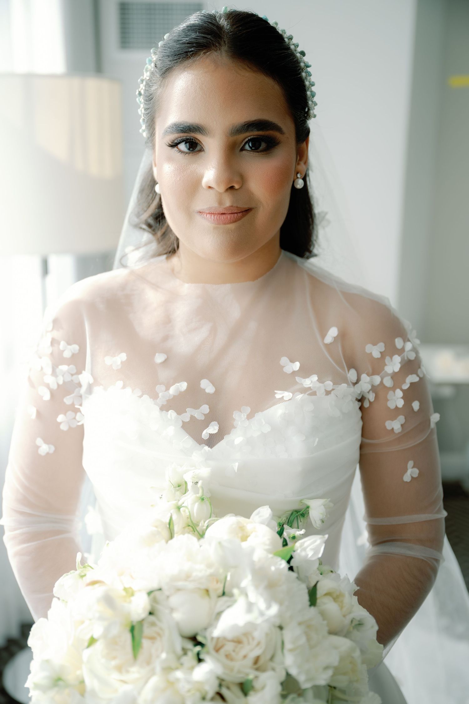 A delicate white bridal bouquet features roses and mixed flowers in a romantic arrangement.