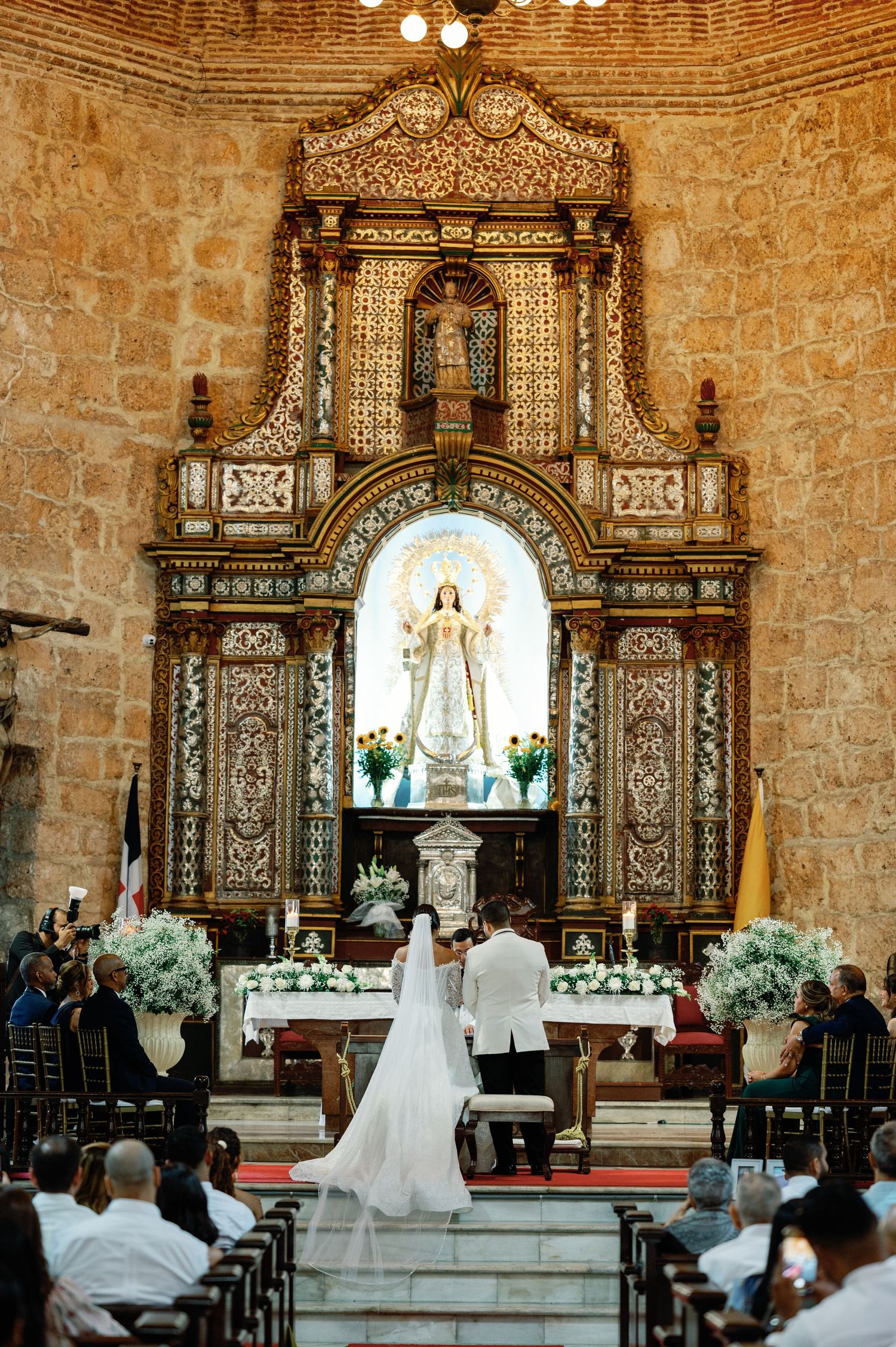 Wedding ceremony taking place inside a historic stone church with ornate altars and decorative elements.