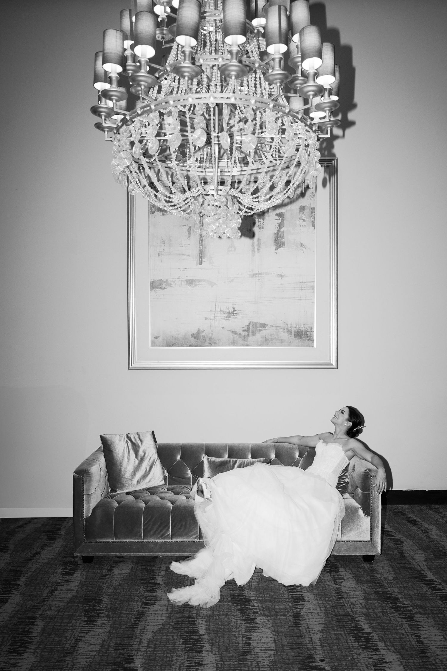 A dramatic black and white photo series showing a person in a white dress floating or levitating under an elegant chandelier.