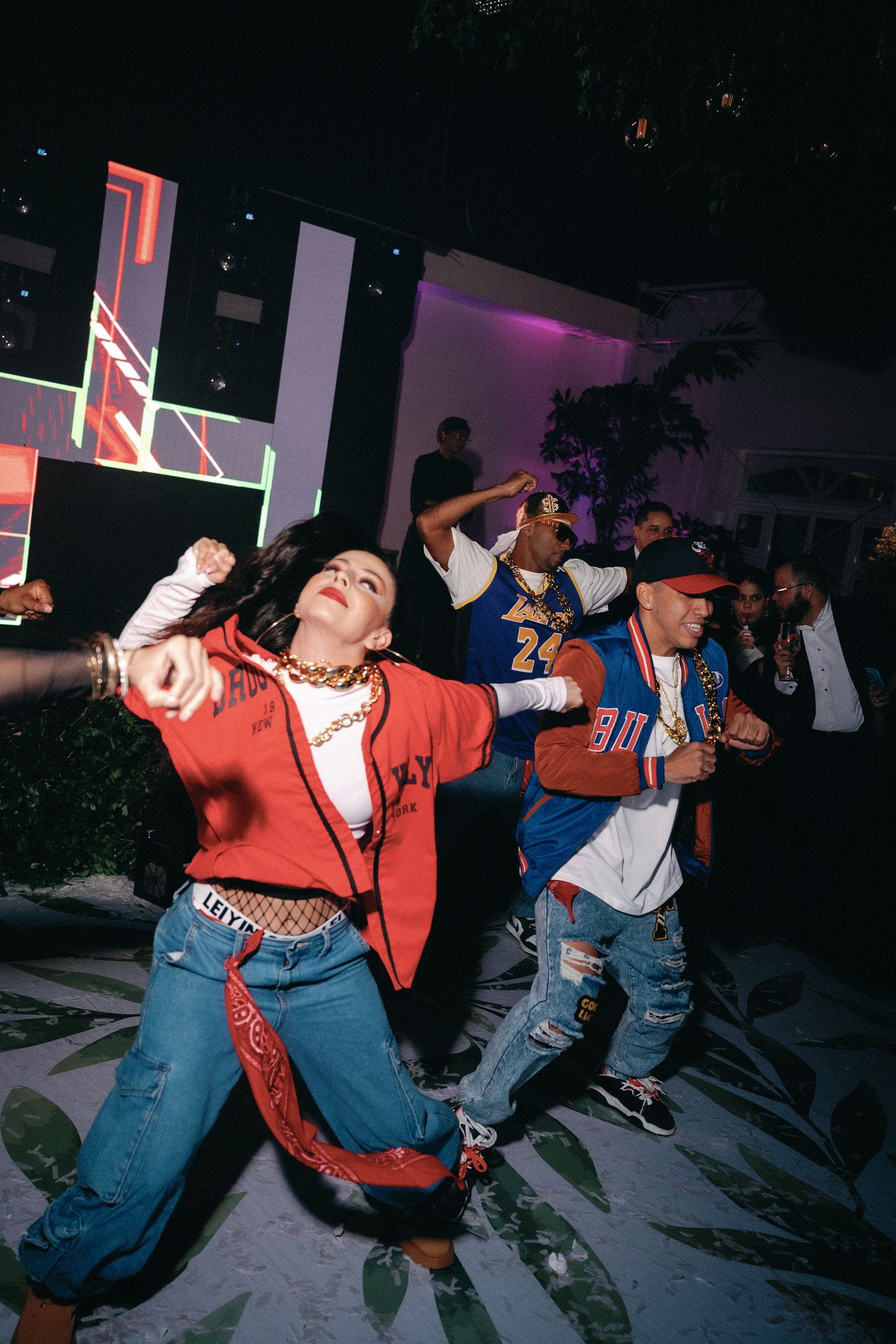 Dancers in 90s style clothing performing energetic dance moves in a line formation.