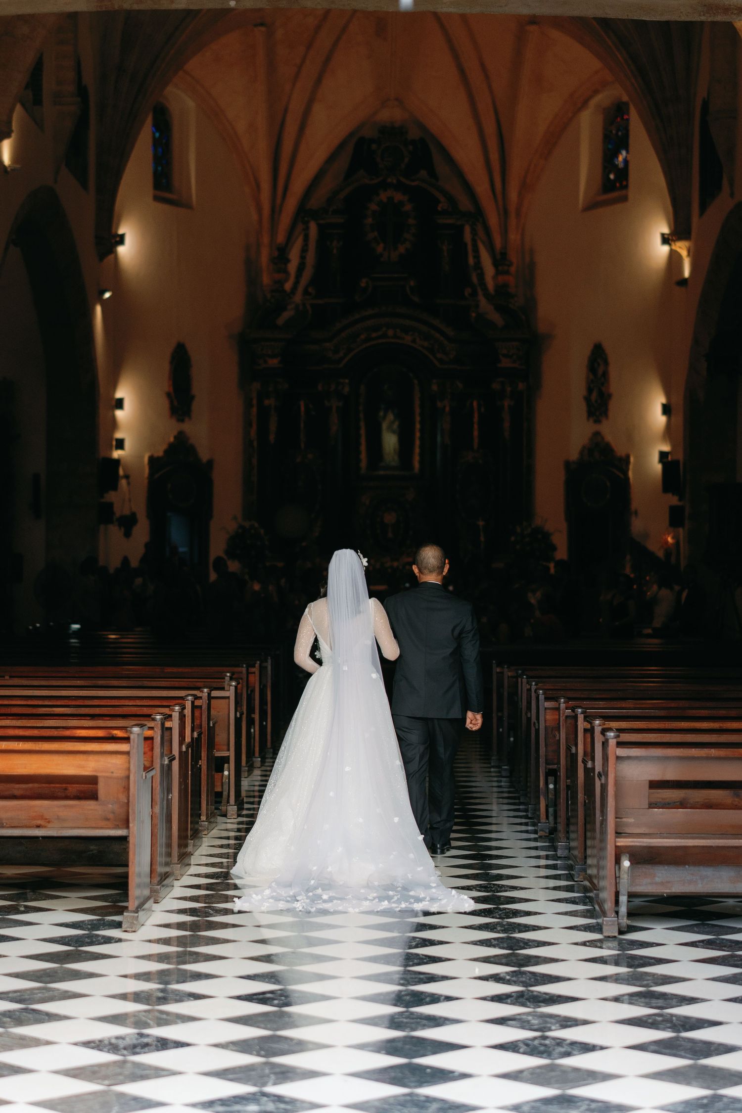 A sequence of photos showing a bride in a white wedding dress walking down a black and white checkered church aisle.