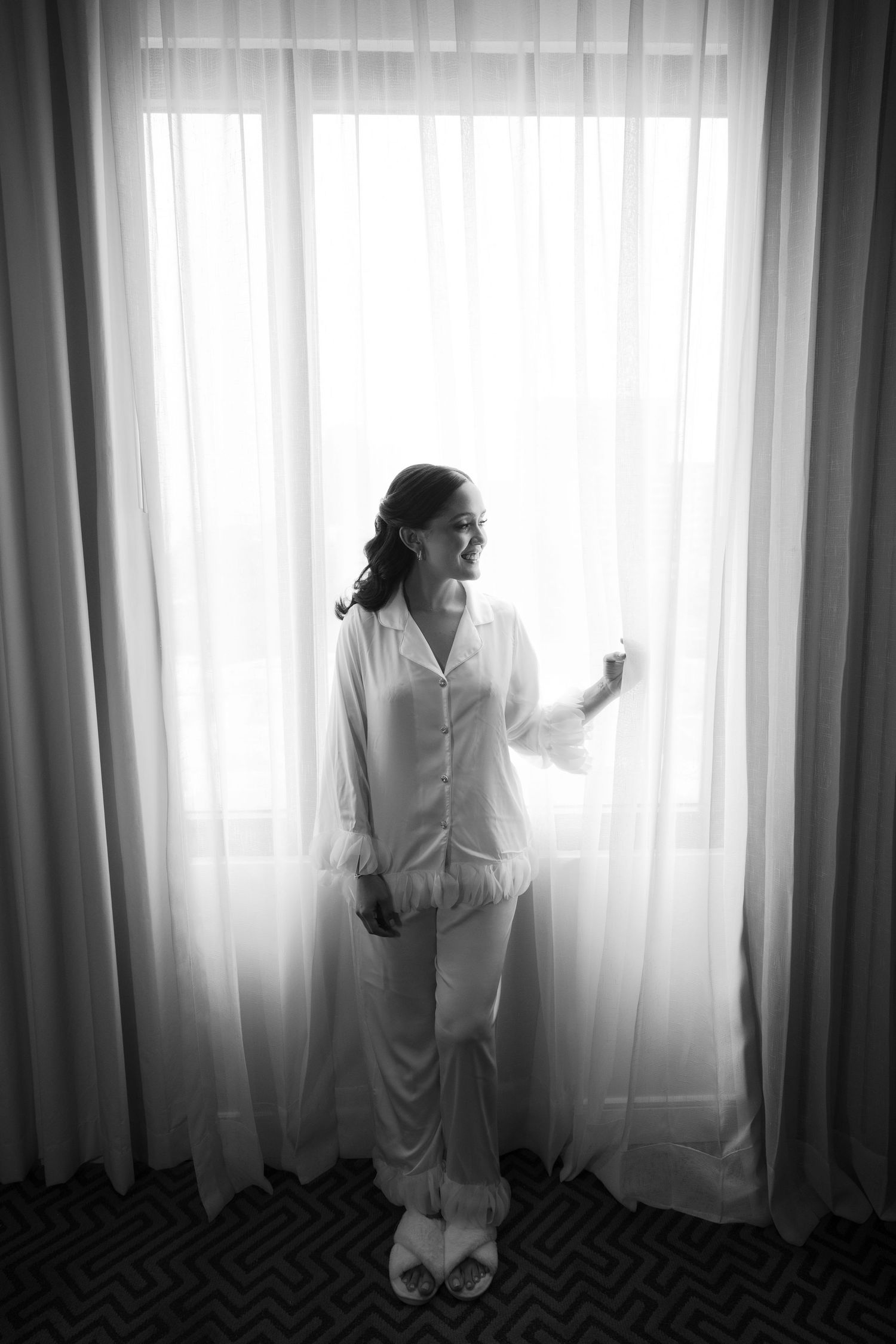 A black and white photo series shows a figure in white standing by curtained windows in four different poses.