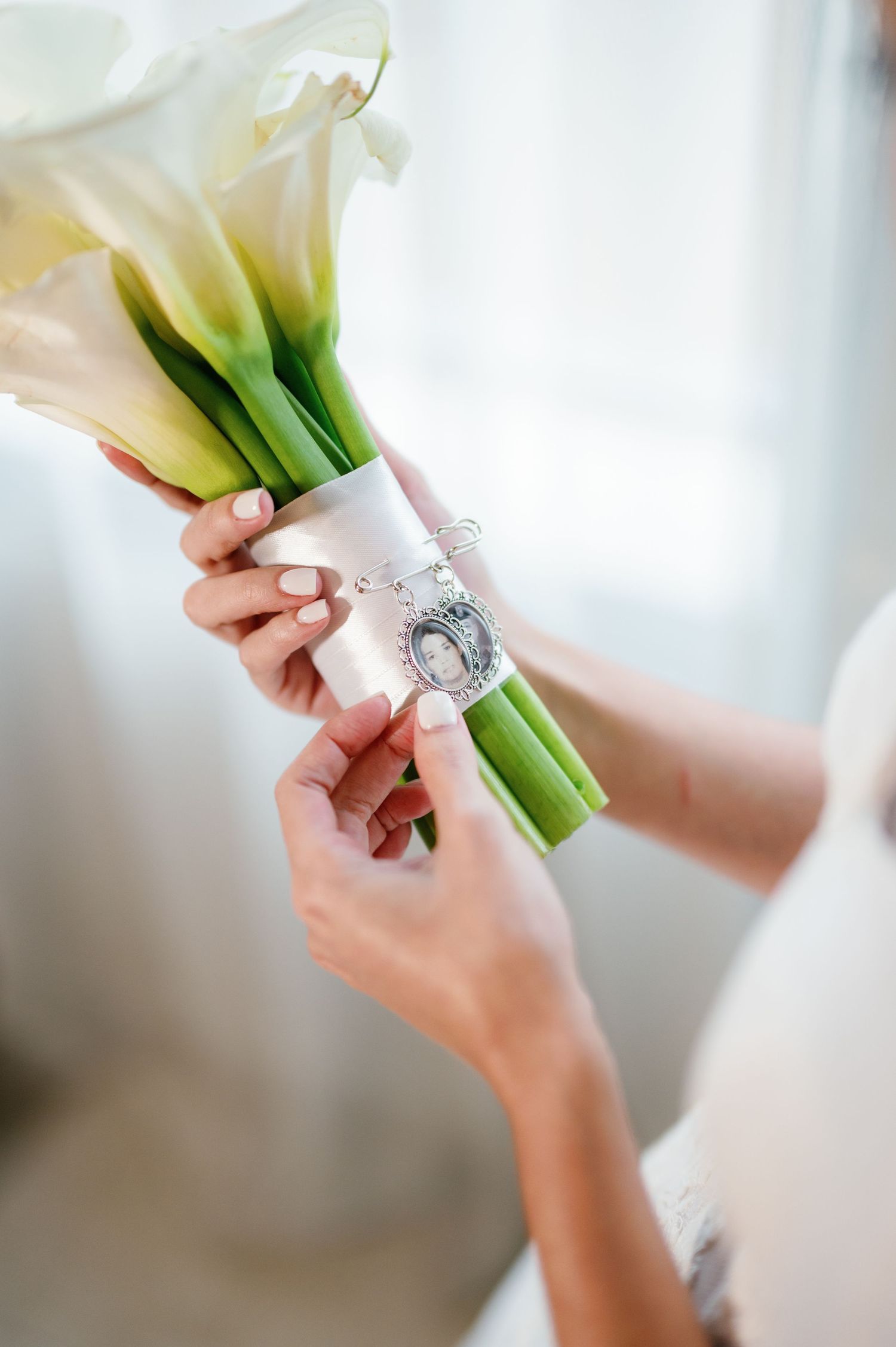 Close-up shots of hands wrapping a bridal bouquet stem with a decorative ribbon and ornament.