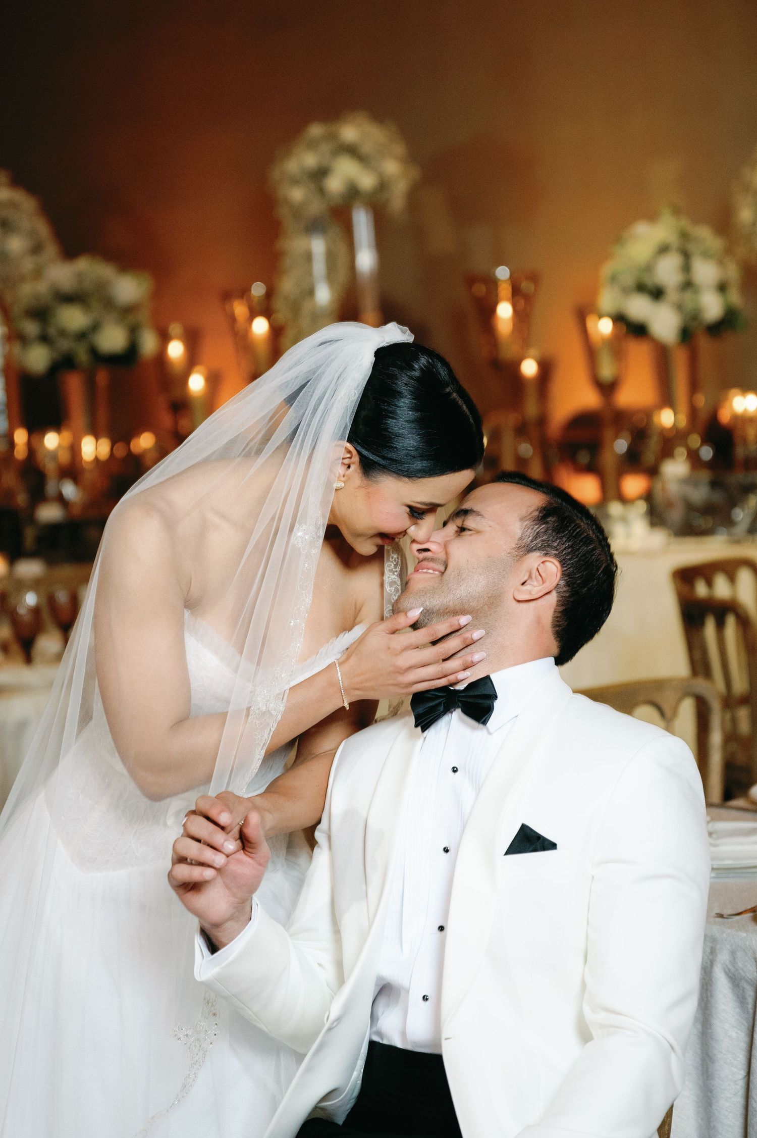 A romantic wedding reception moment captured in a sequence showing a tender kiss under warm candlelight.