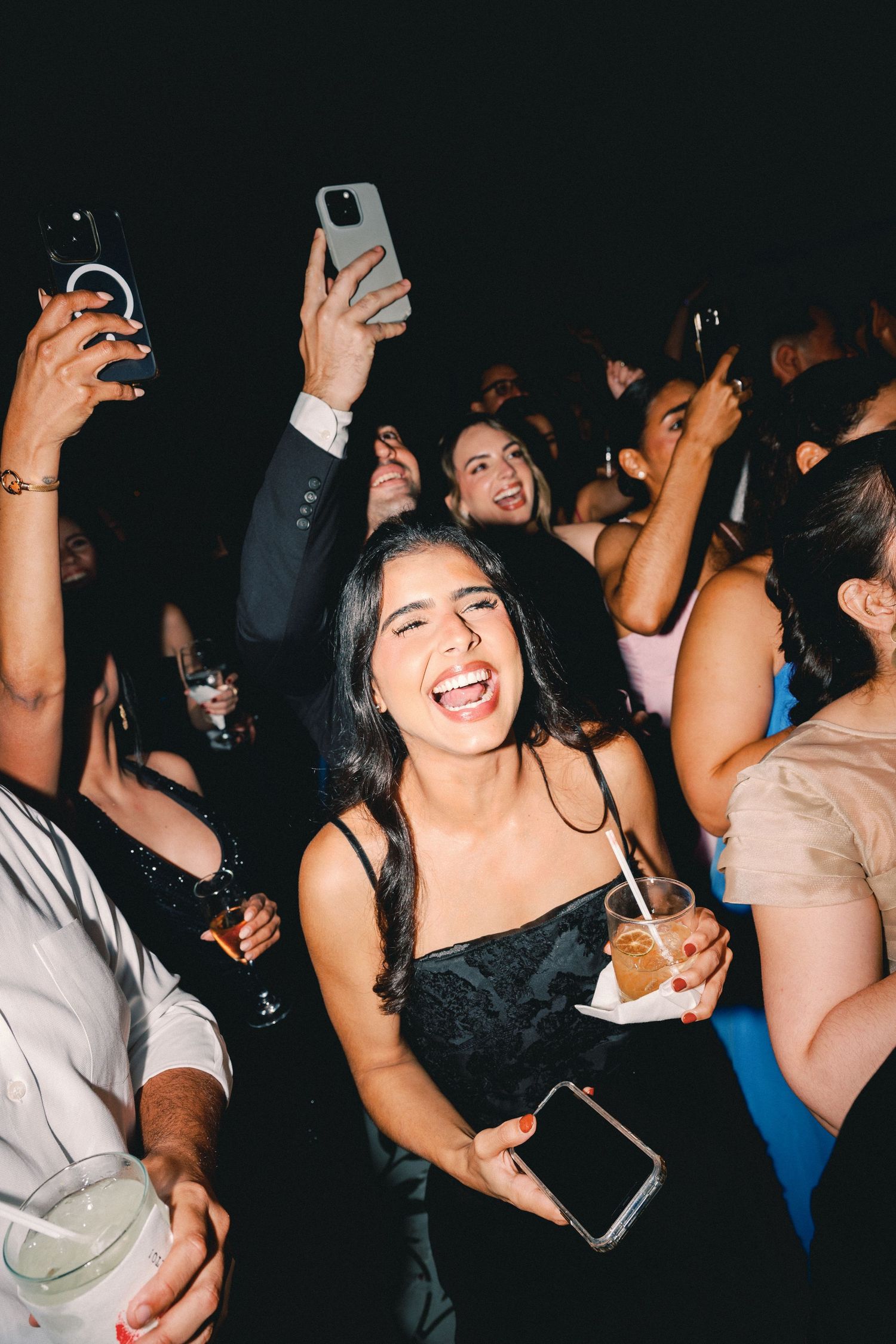 People dancing and celebrating at a lively nighttime party with hands raised in the air.