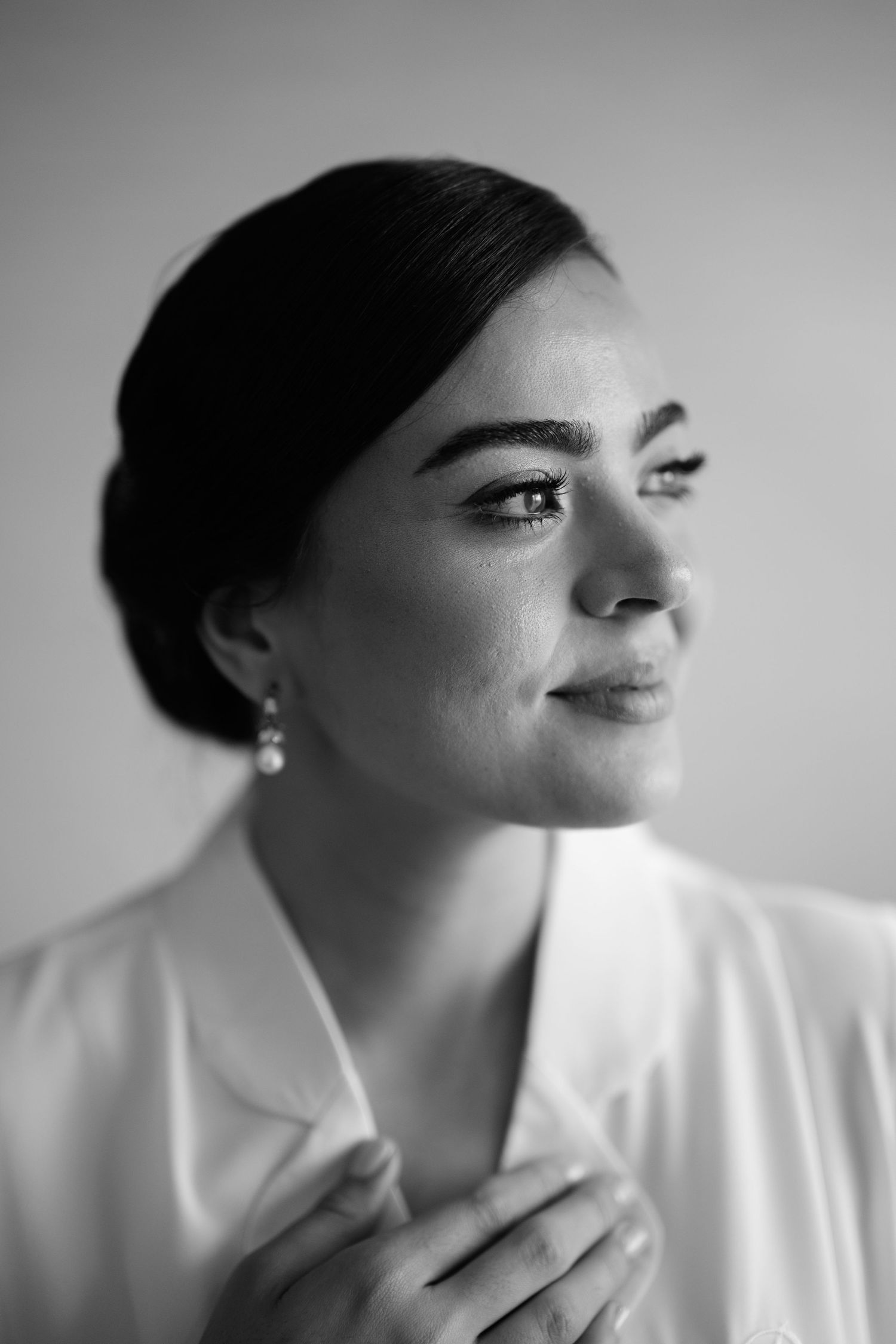 A series of black and white profile portraits showing a person in a white shirt with elegant makeup and pearl earrings.