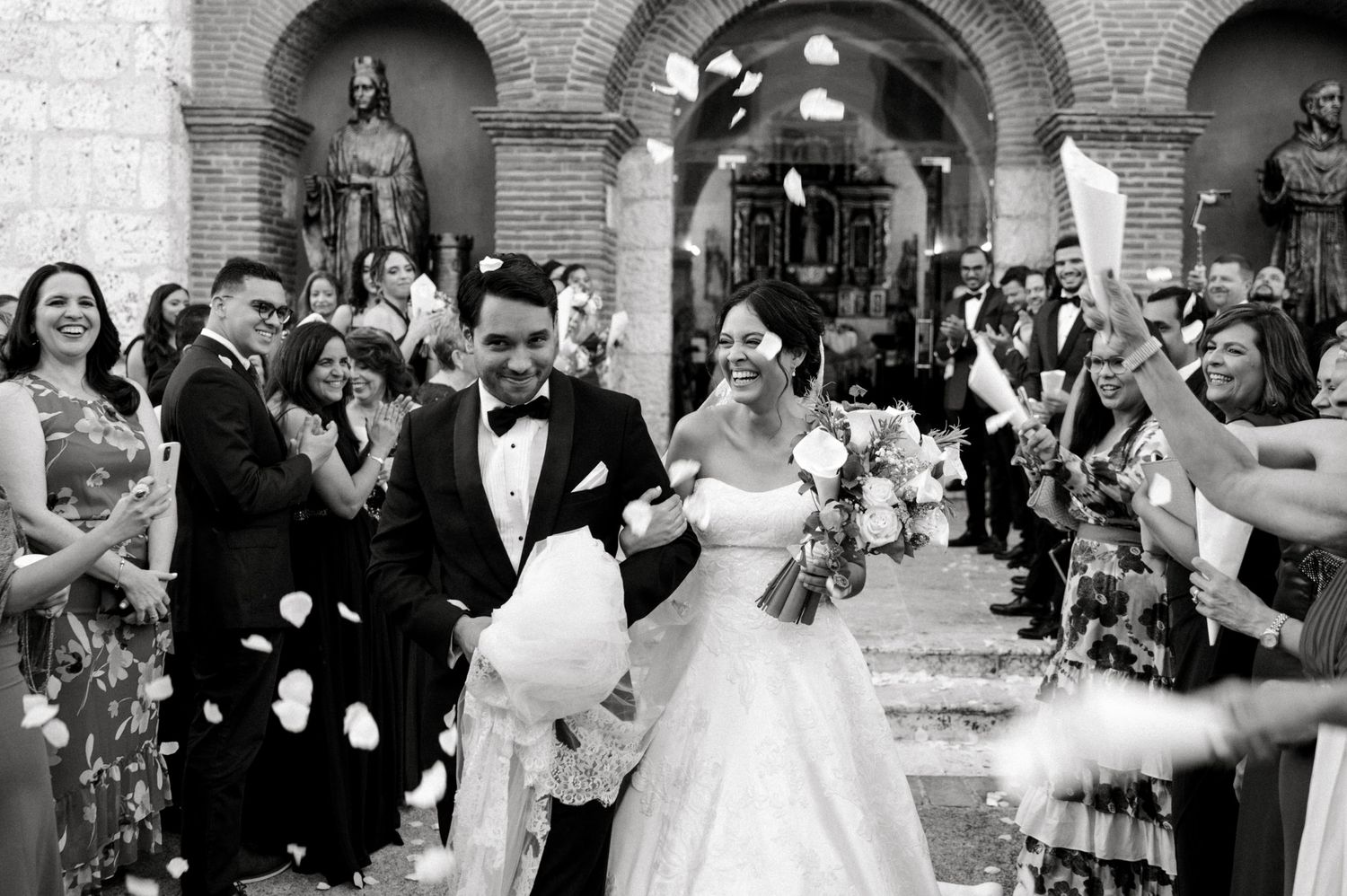 Elegant outdoor wedding ceremony setup with stone archways and scattered rose petals.