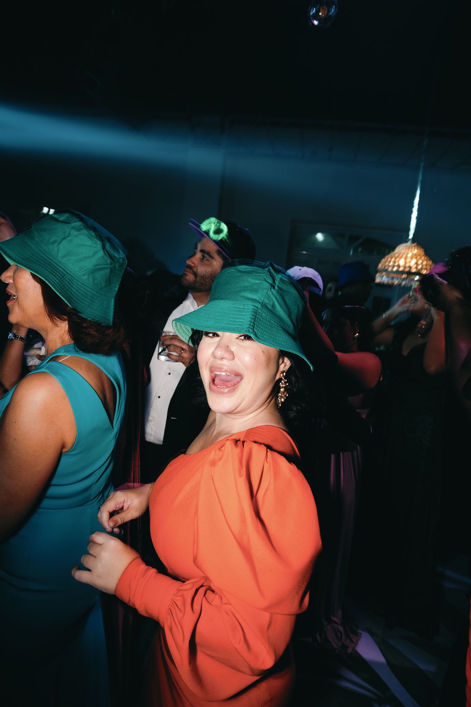 People dancing and celebrating at a dimly lit nightclub with colorful lighting effects.