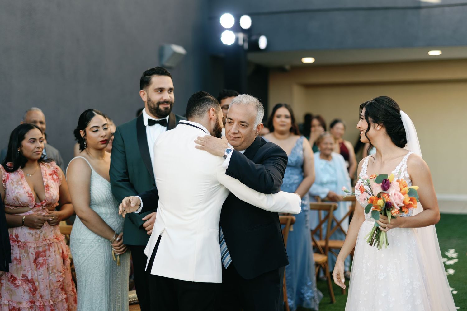 Couples dance together during a wedding reception in an elegant indoor venue with warm lighting.