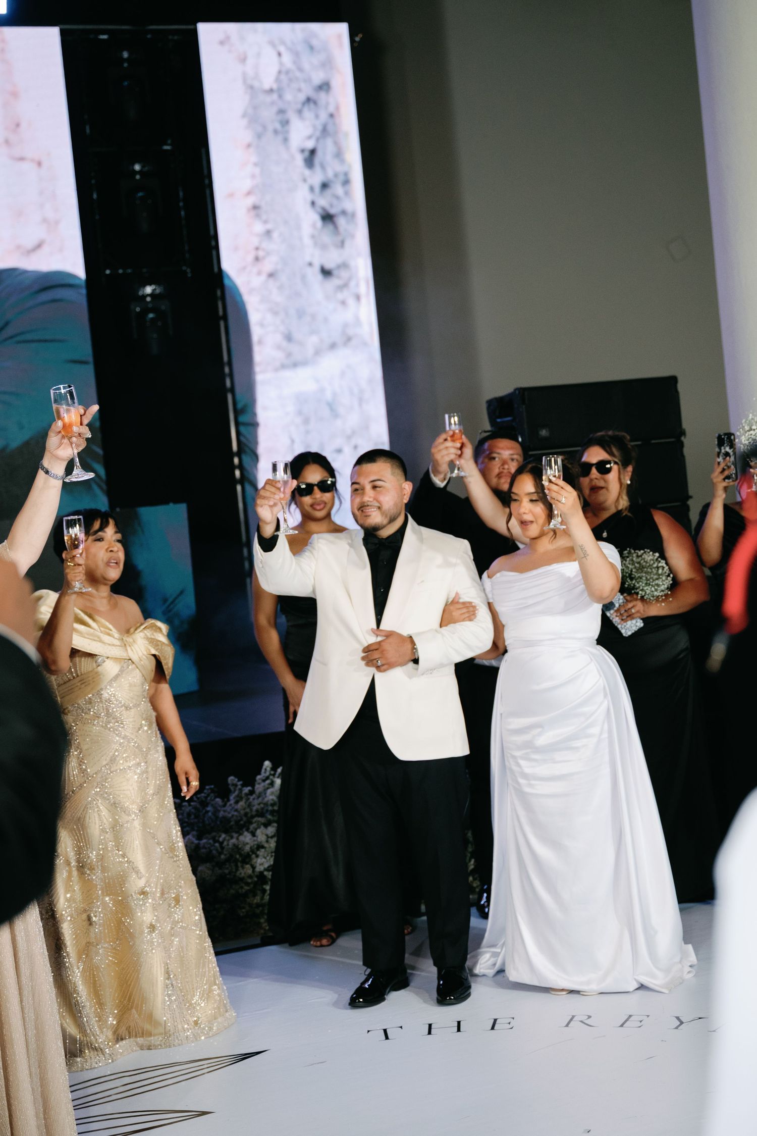 Wedding celebration with guests raising champagne glasses in a toast during an elegant reception.