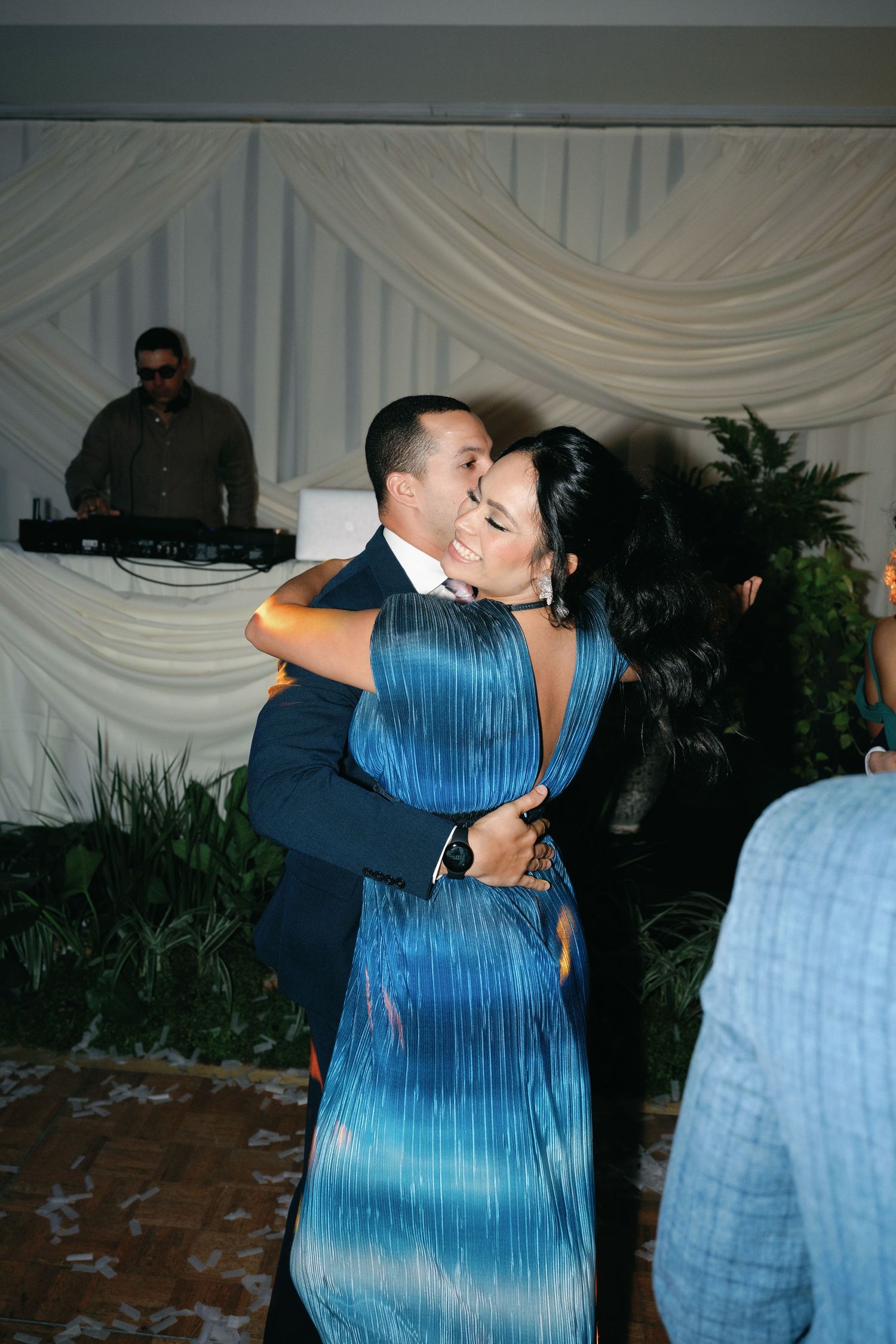 Dancing couple in formal attire share an intimate moment on a petal-covered dance floor.