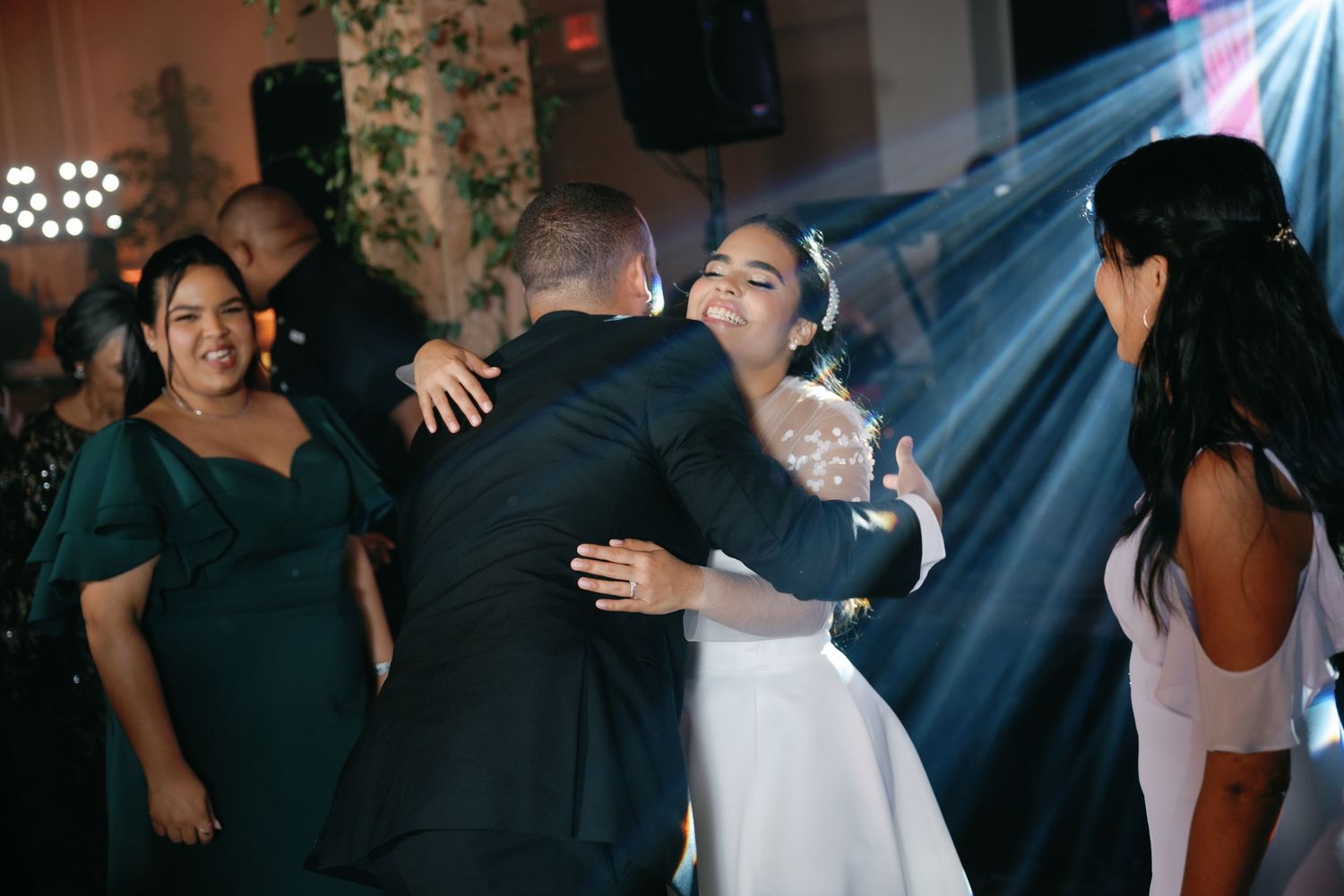 Energetic dance party scene at a wedding reception with blue lighting effects and dancing guests.