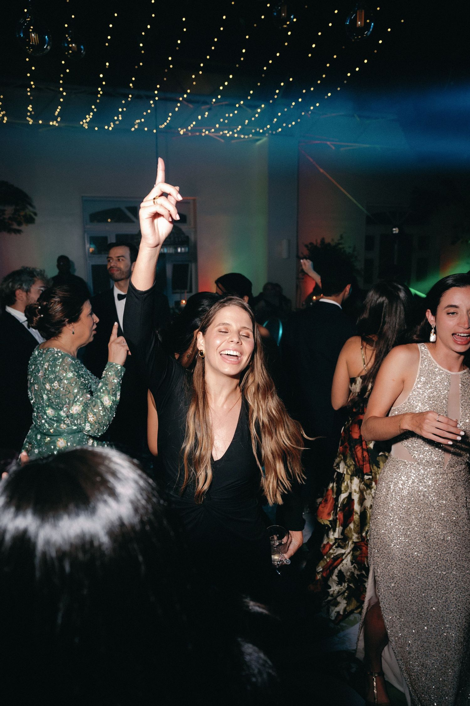 People dancing and celebrating under string lights at a nighttime party.