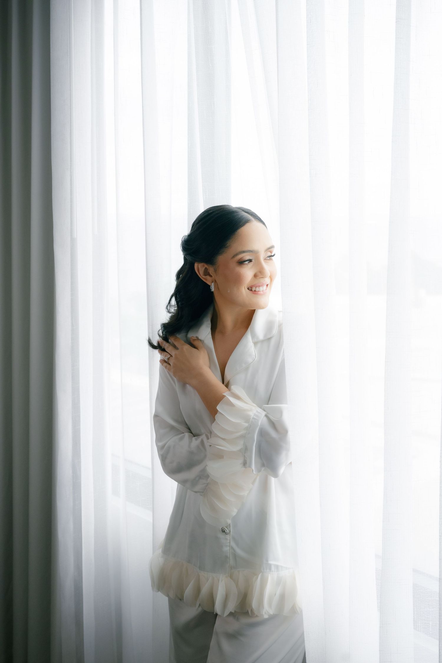 A person in a white outfit poses gracefully against sheer curtains in a series of artistic portrait shots.