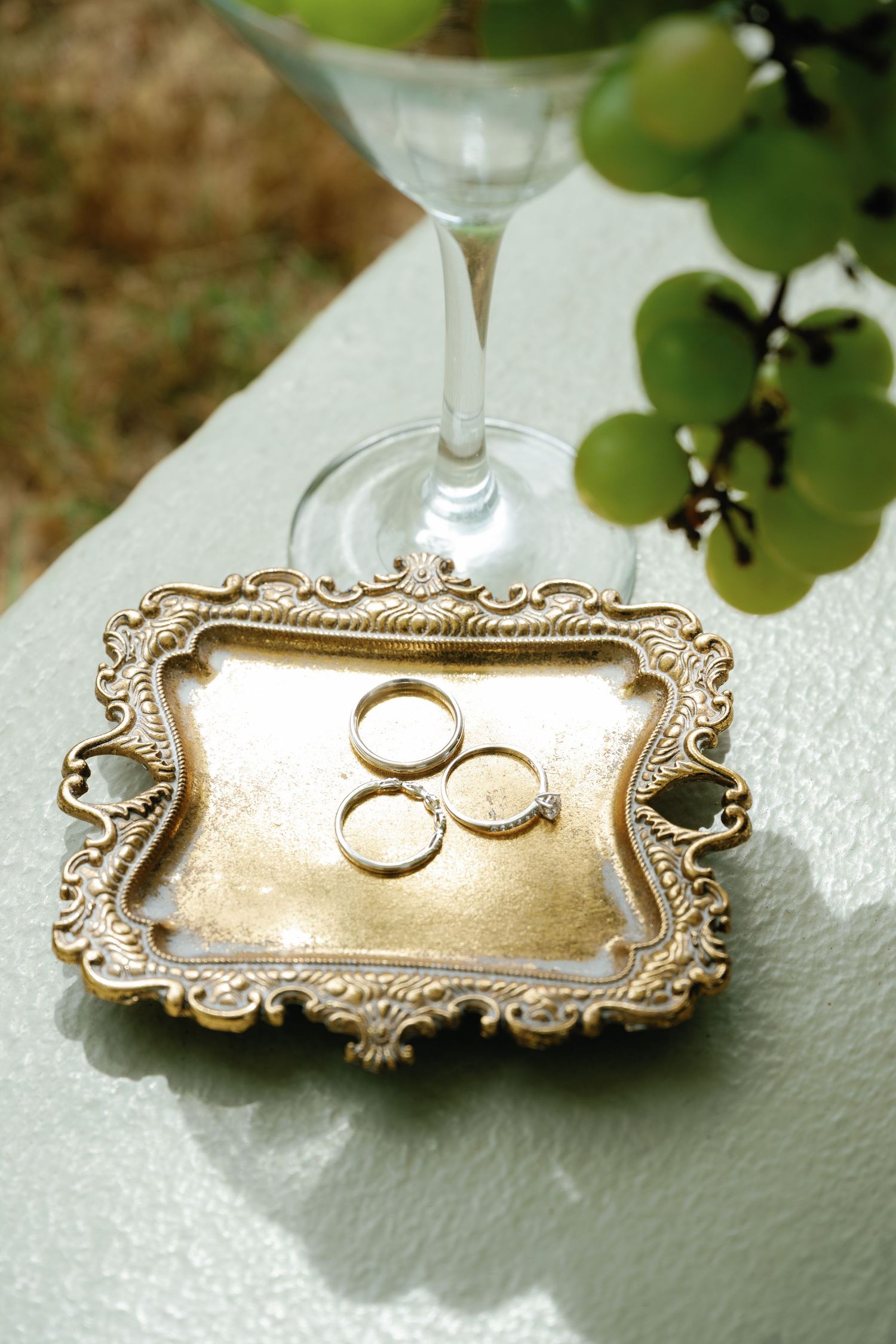 Wedding rings displayed on an ornate vintage gold tray with delicate floral details and scrollwork.
