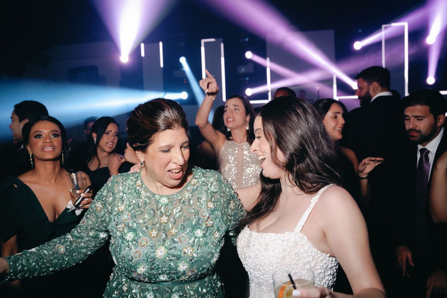 Crowded dance floor with purple lighting and people enjoying a lively party atmosphere.