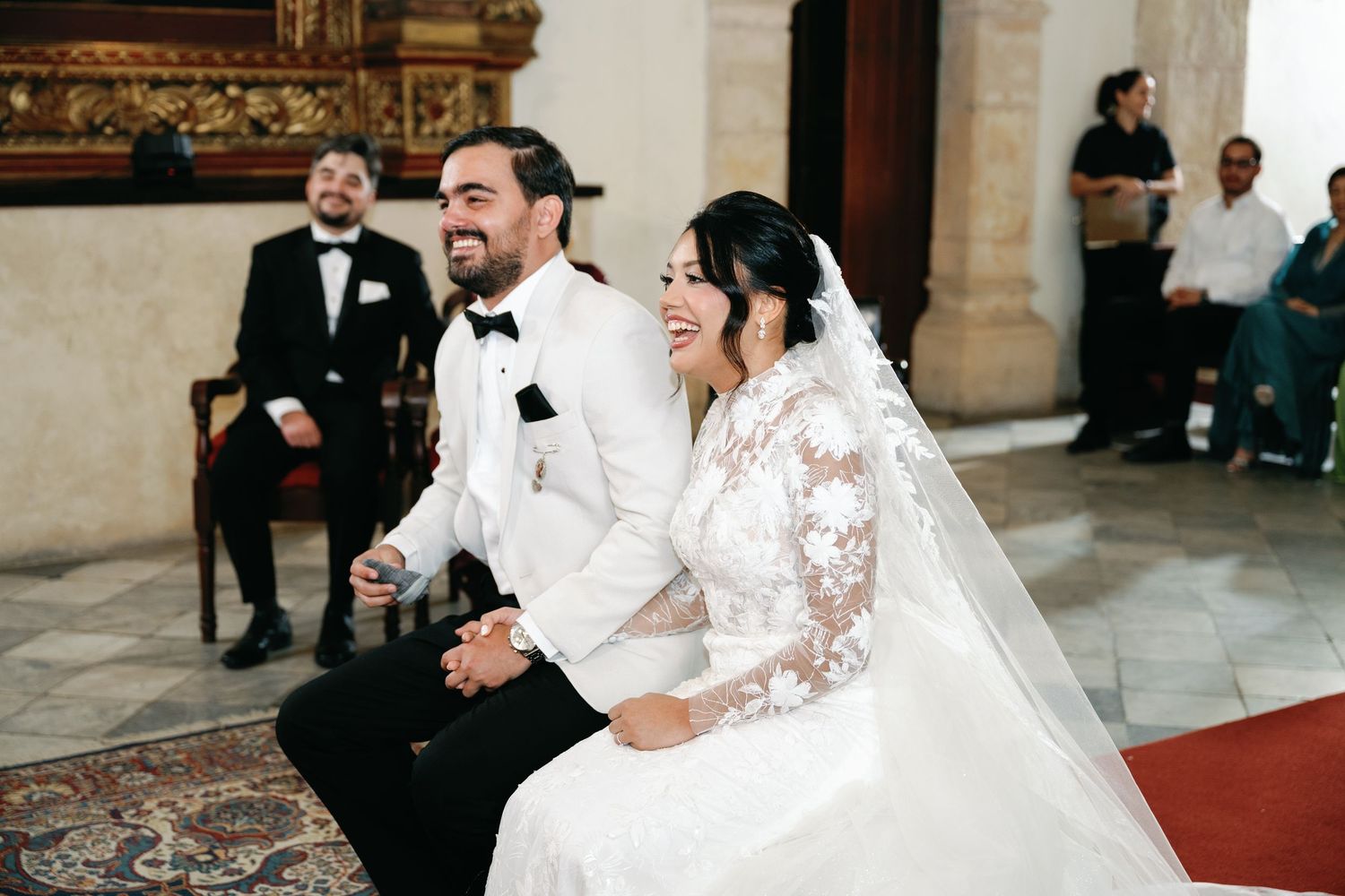 A bride and groom share a joyful moment during their wedding ceremony in an elegant church setting.