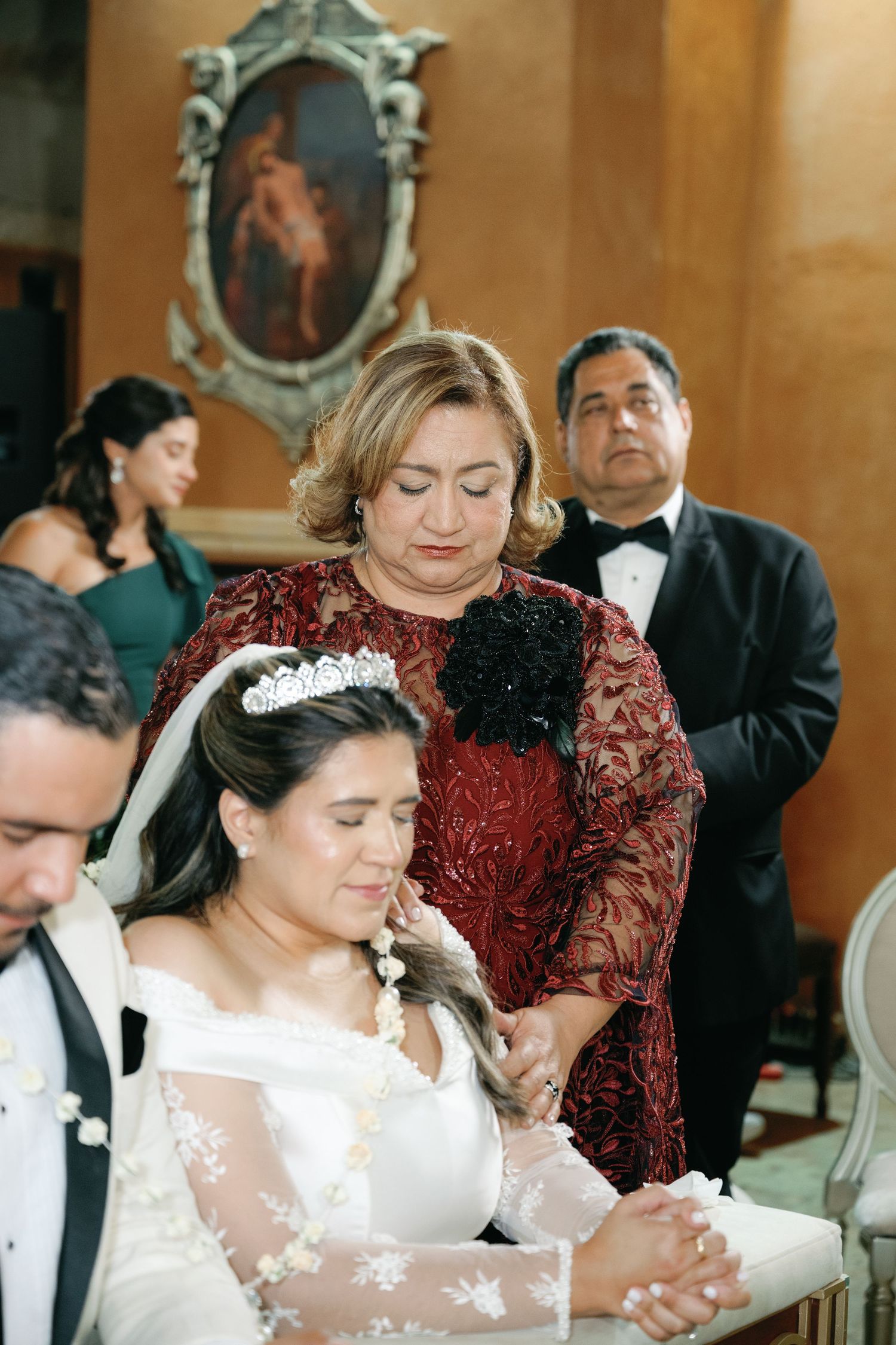 Wedding ceremony attendees in formal attire seated in pews with burgundy accents.