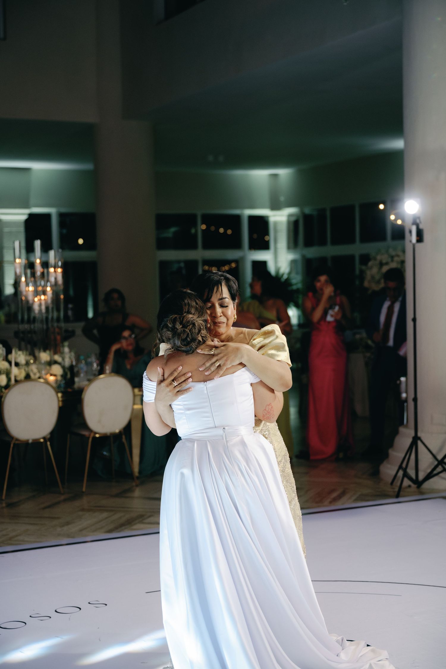 A couple shares an intimate dance moment on an illuminated white dance floor at their wedding reception.