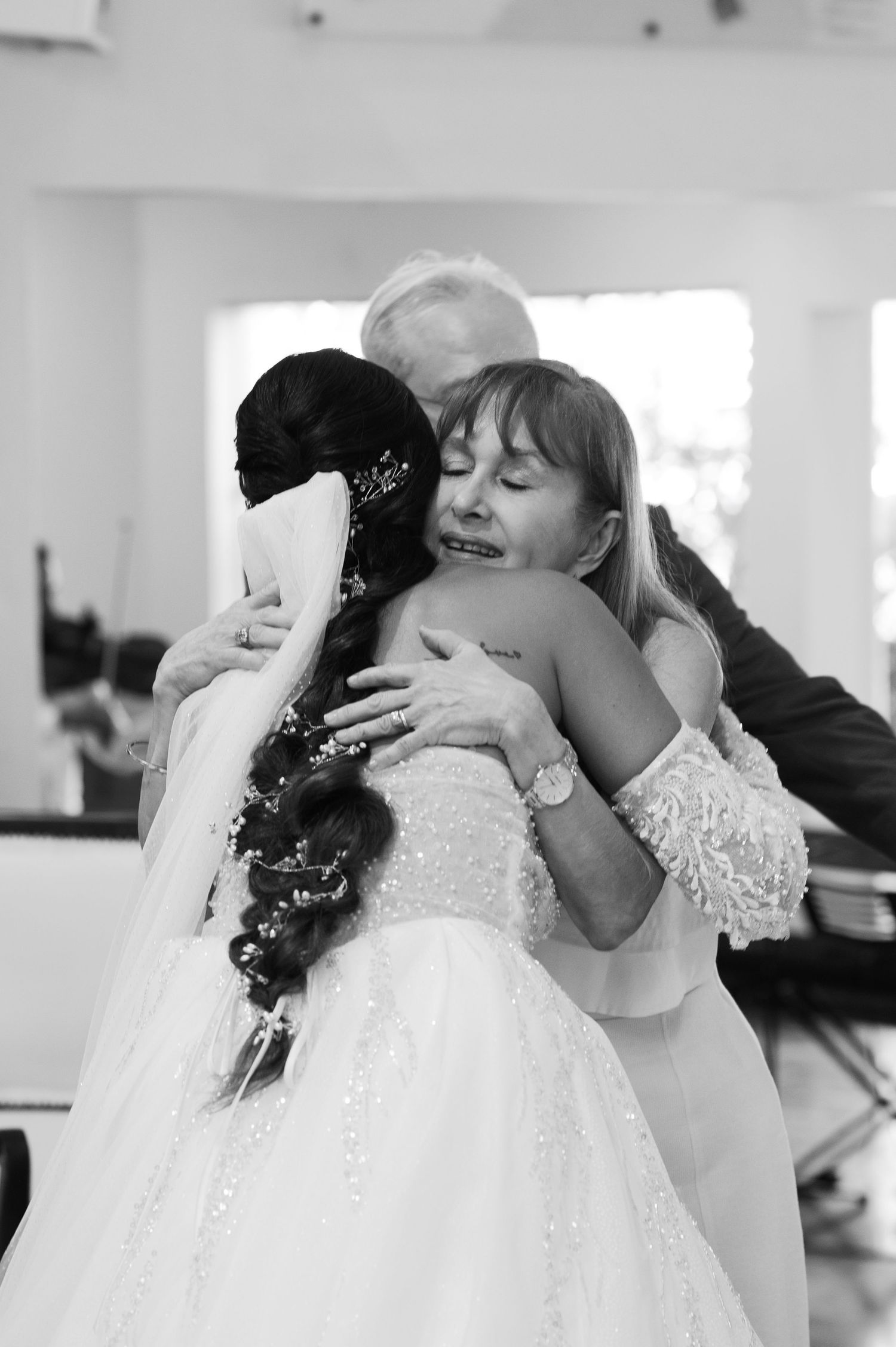 A heartfelt embrace between two people at a wedding, with one wearing a beautiful white lace gown.