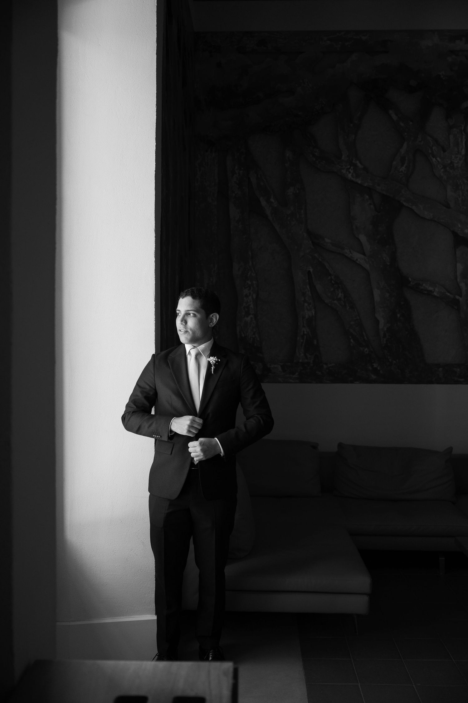 Dramatic black and white sequence showing a figure in a suit emerging from shadows against a stark wall.