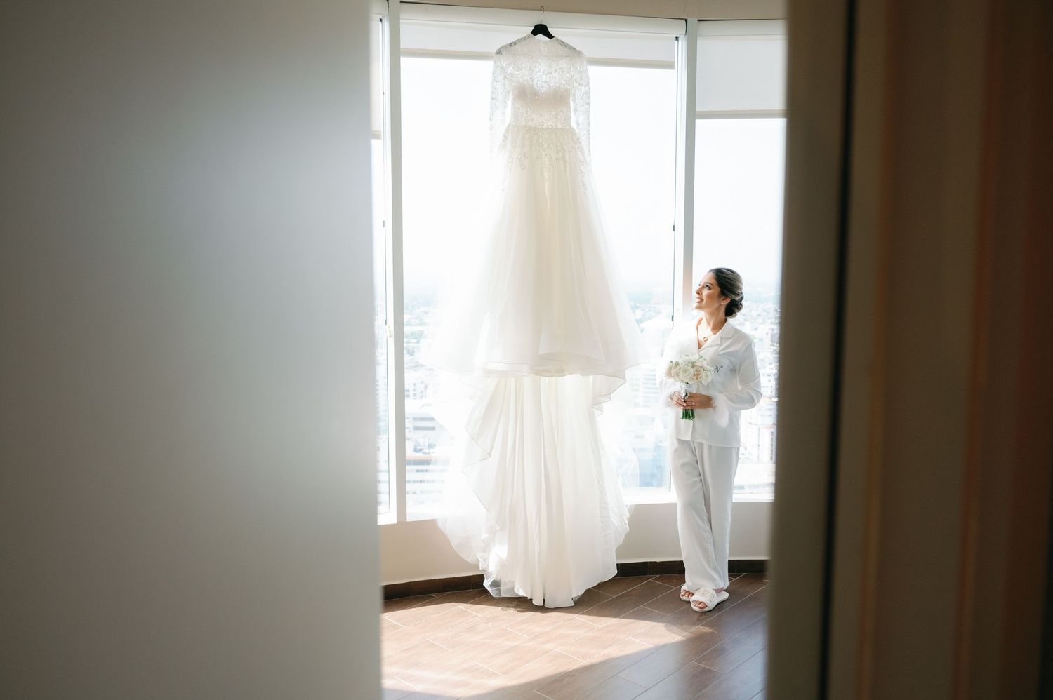 Wedding dress and formal attire hanging in preparation for a ceremony in a bright room.