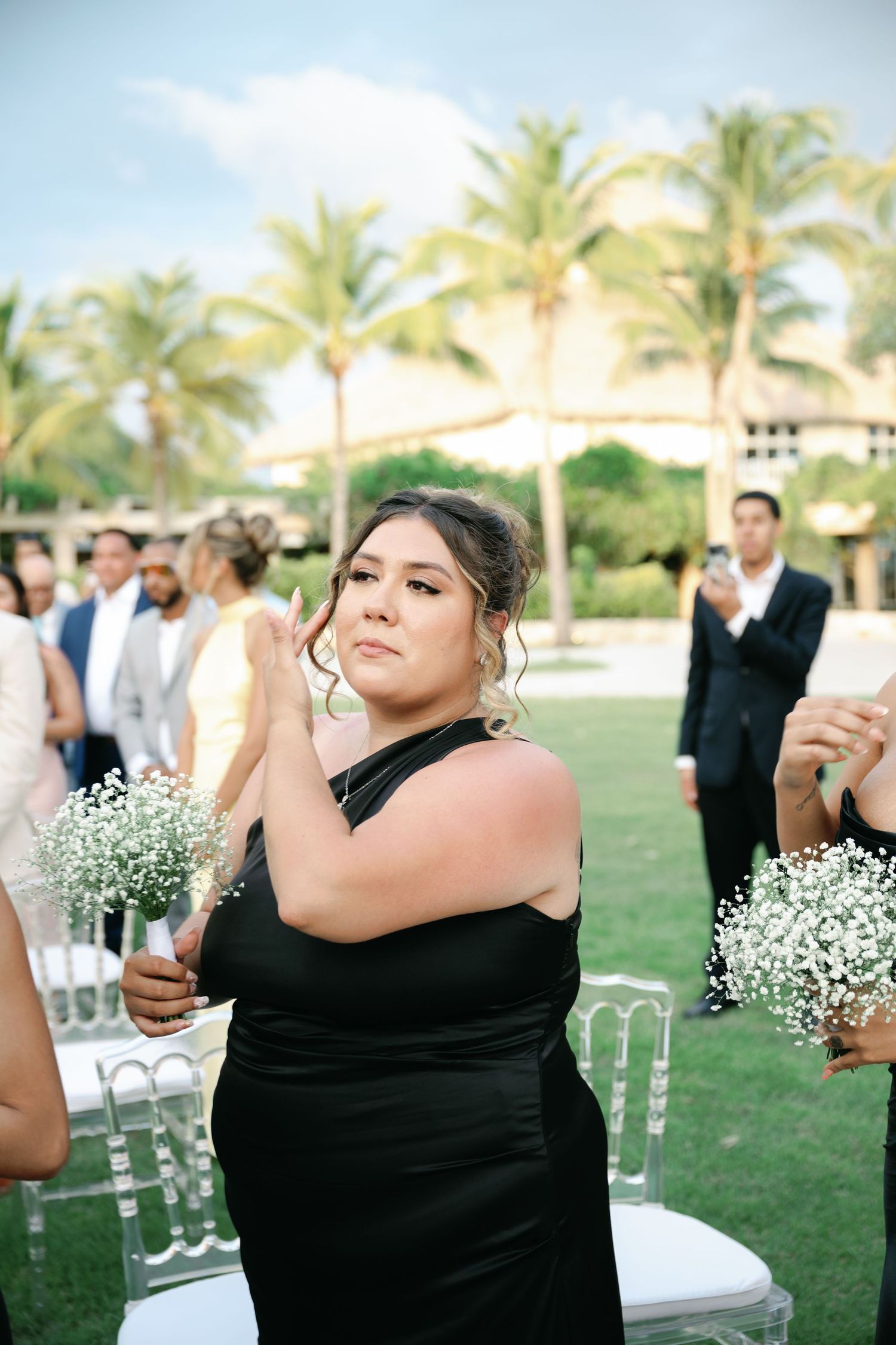 Wedding decorations being set up with white chairs and baby's breath flowers against a backdrop of palm trees.