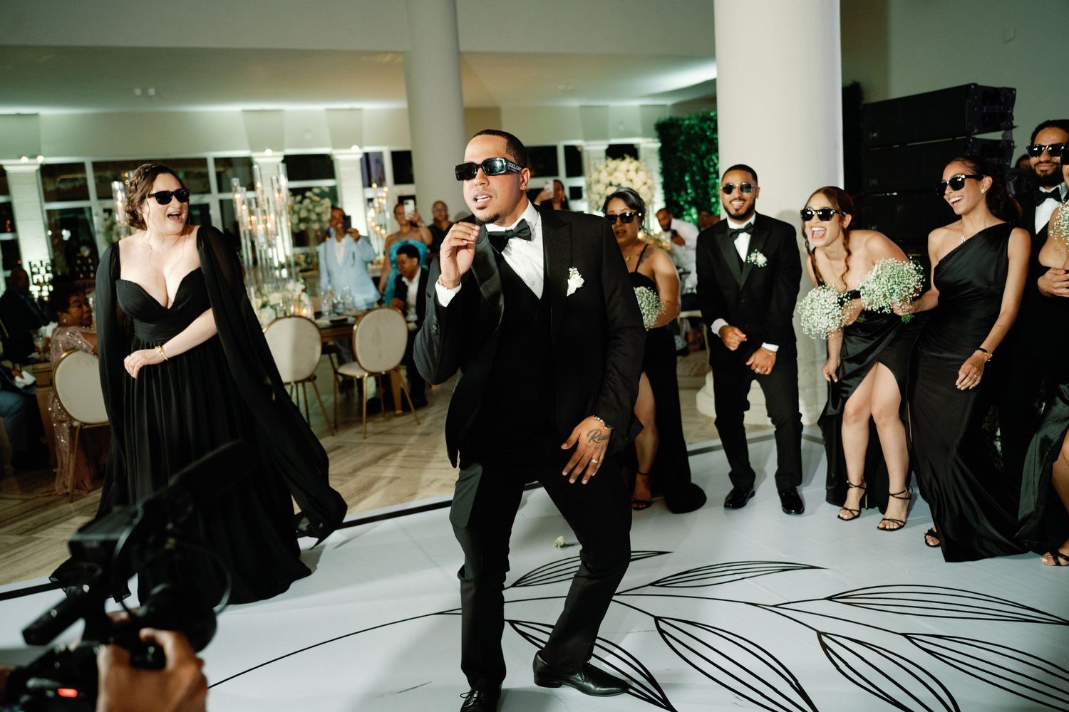 Wedding guests dance and celebrate on a black and white patterned dance floor at an elegant reception party.