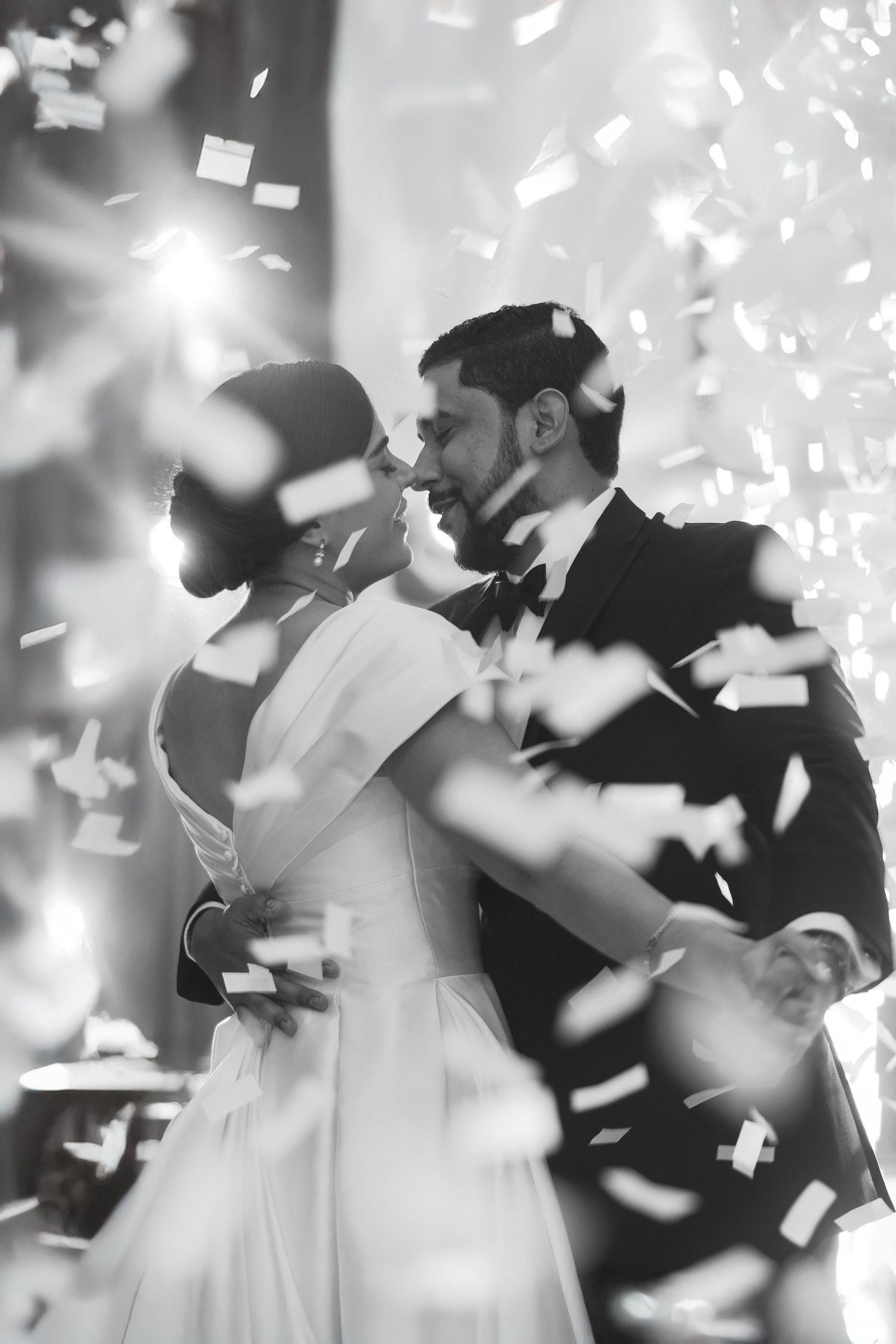 Romantic wedding couple dancing surrounded by falling confetti during their first dance at reception.