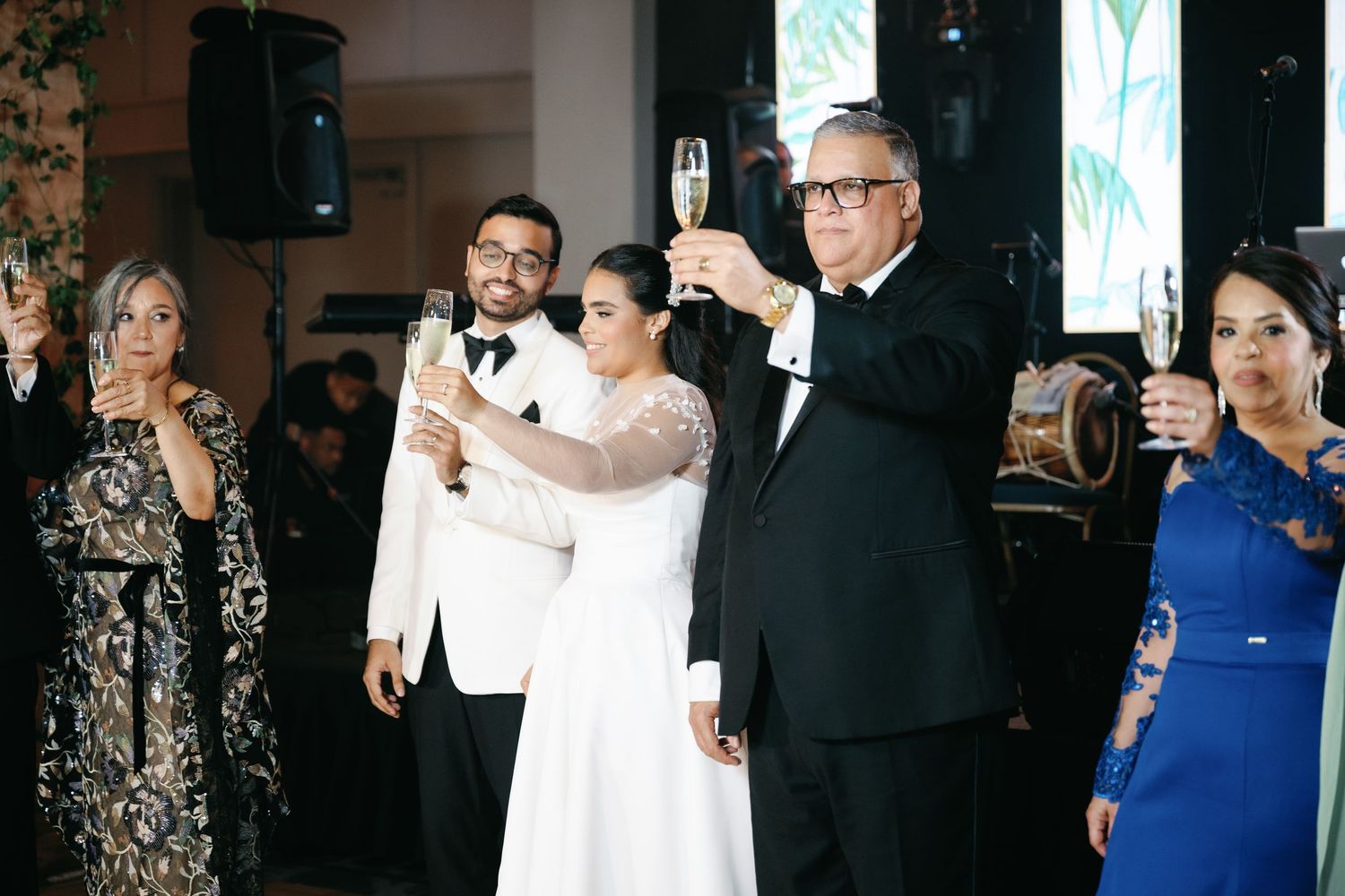 Wedding guests raise their glasses in a toast during an elegant reception celebration.