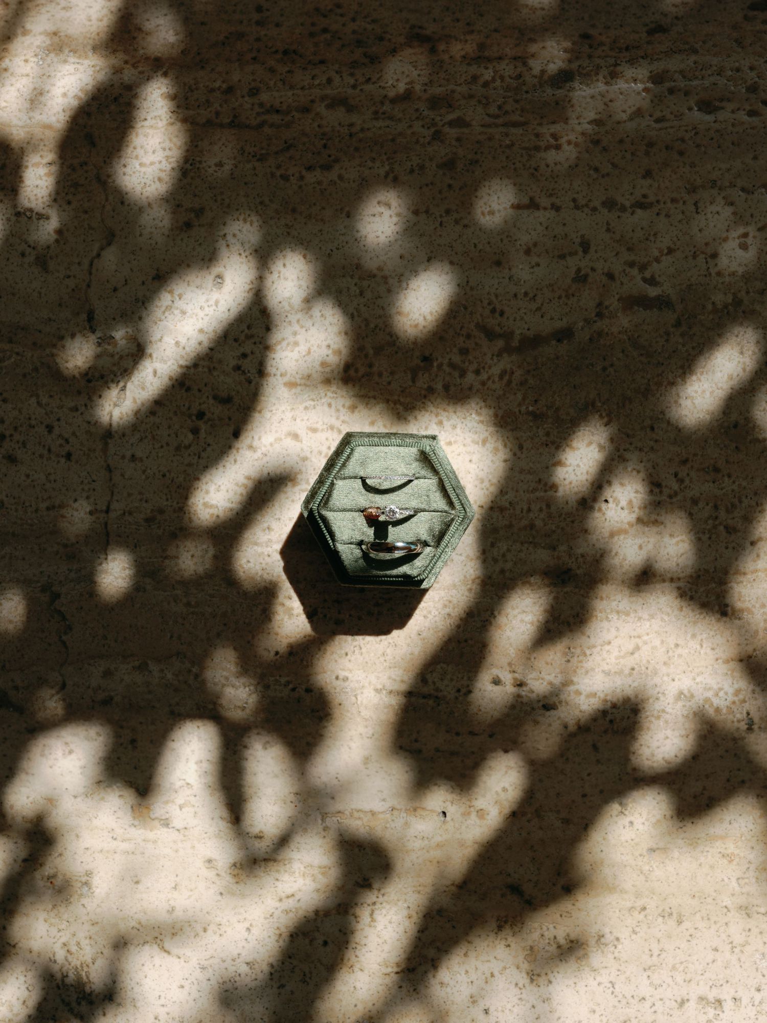 A hexagonal metal bolt with a medical caduceus symbol cast in dappled sunlight and shadows.