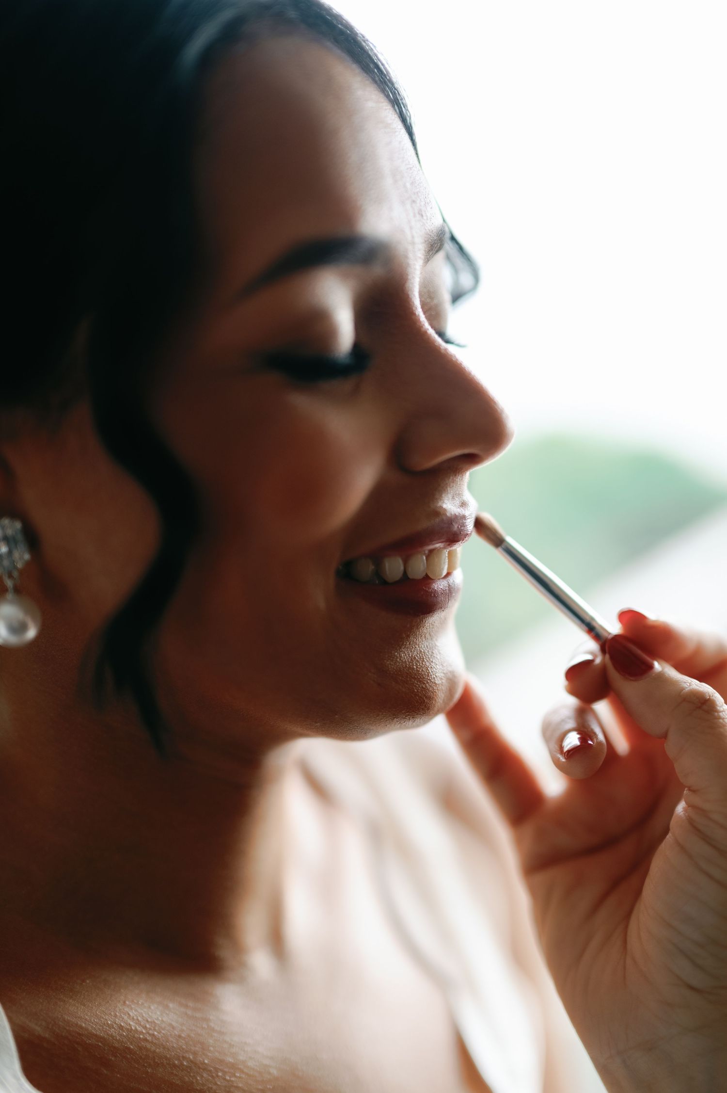 A makeup artist applies cosmetics to someone's face in a series of close-up shots showing the application process.