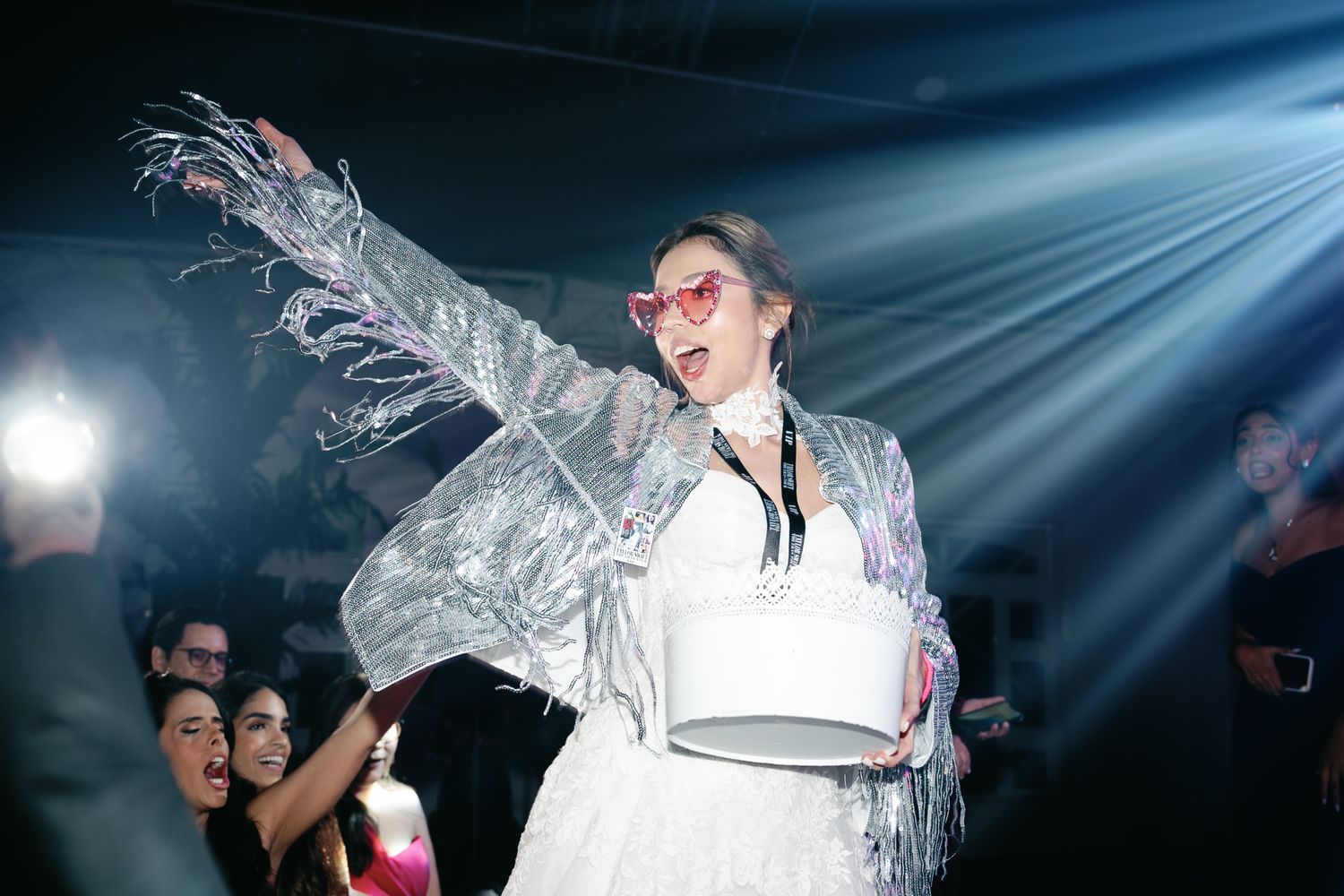 A performer in a white outfit dances energetically on stage under dramatic blue lighting during a concert performance.