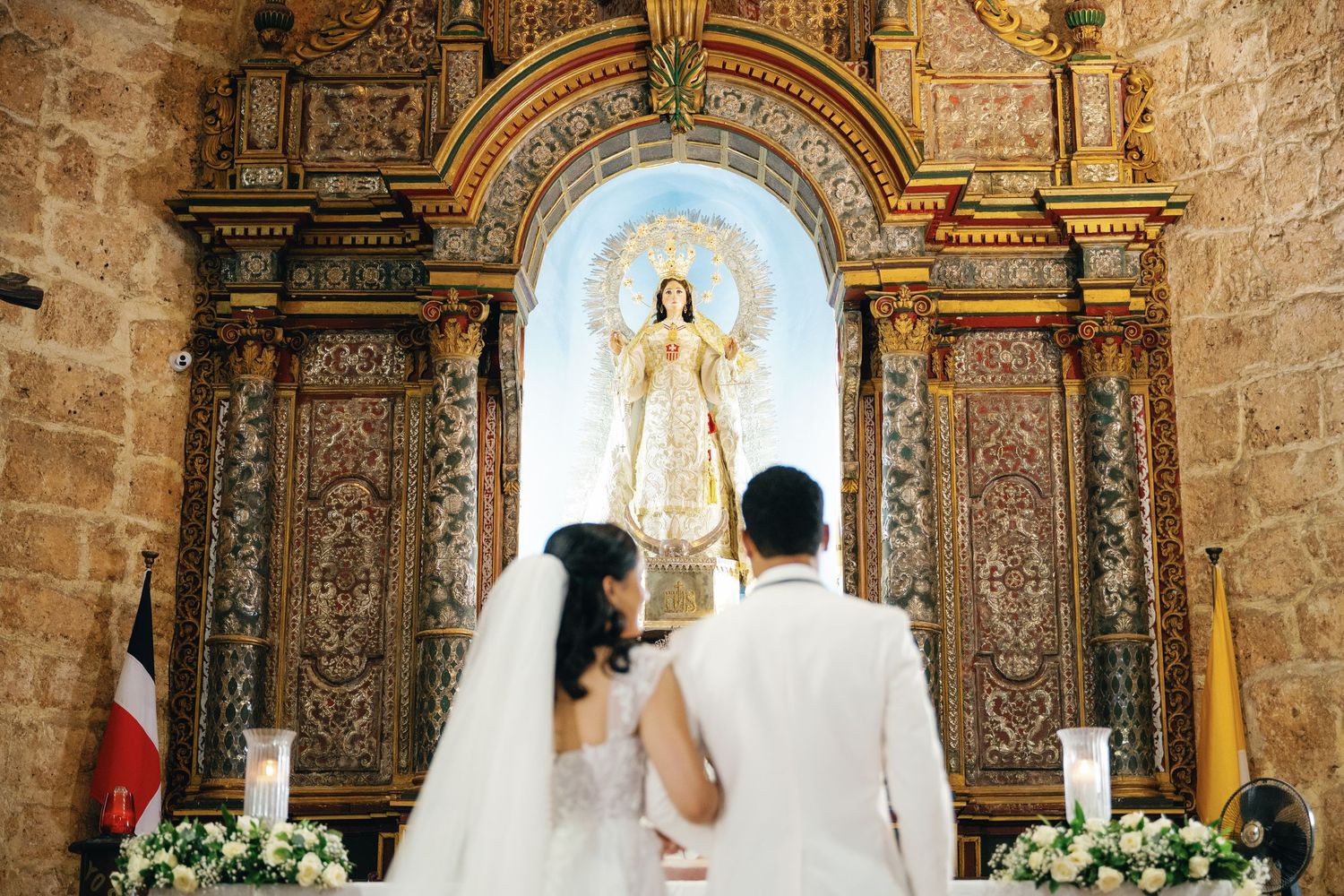 Ornate baroque altar with religious artwork and gold details inside a stone church.