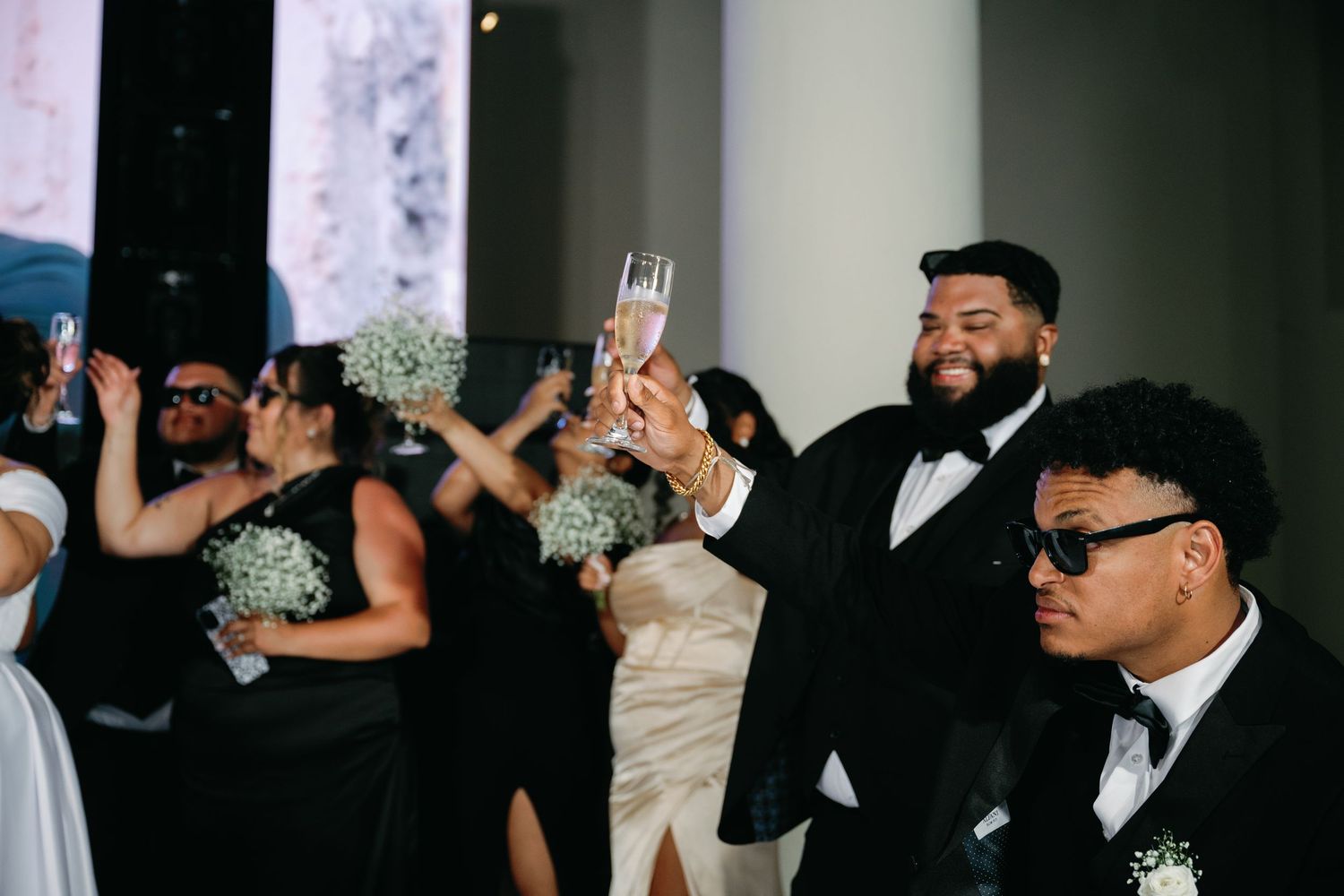 Wedding guests raise their arms and dance together during a joyful celebration at a reception.
