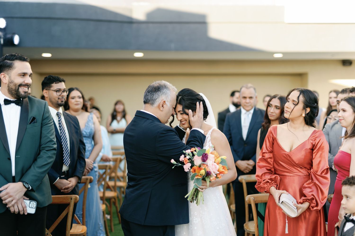 Wedding guests mingle and celebrate during an outdoor reception with colorful decor and floral arrangements.