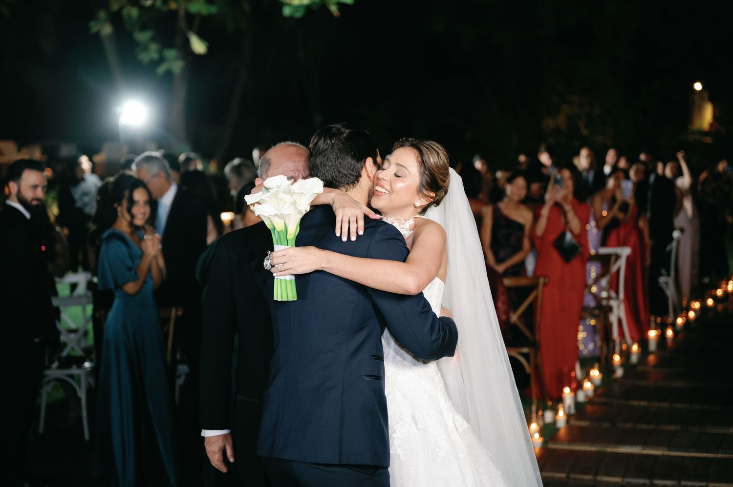 Wedding guests dance and celebrate during an evening reception with string lights illuminating the outdoor venue.
