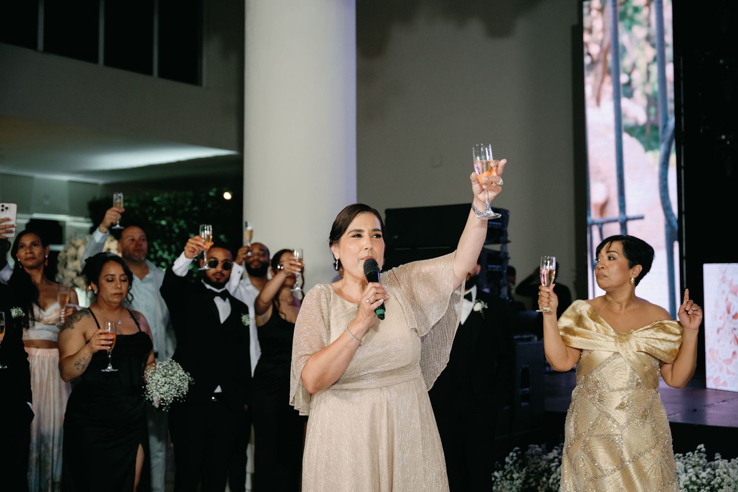 A person in a gold evening gown performs on stage with dramatic lighting and gestures during a performance.