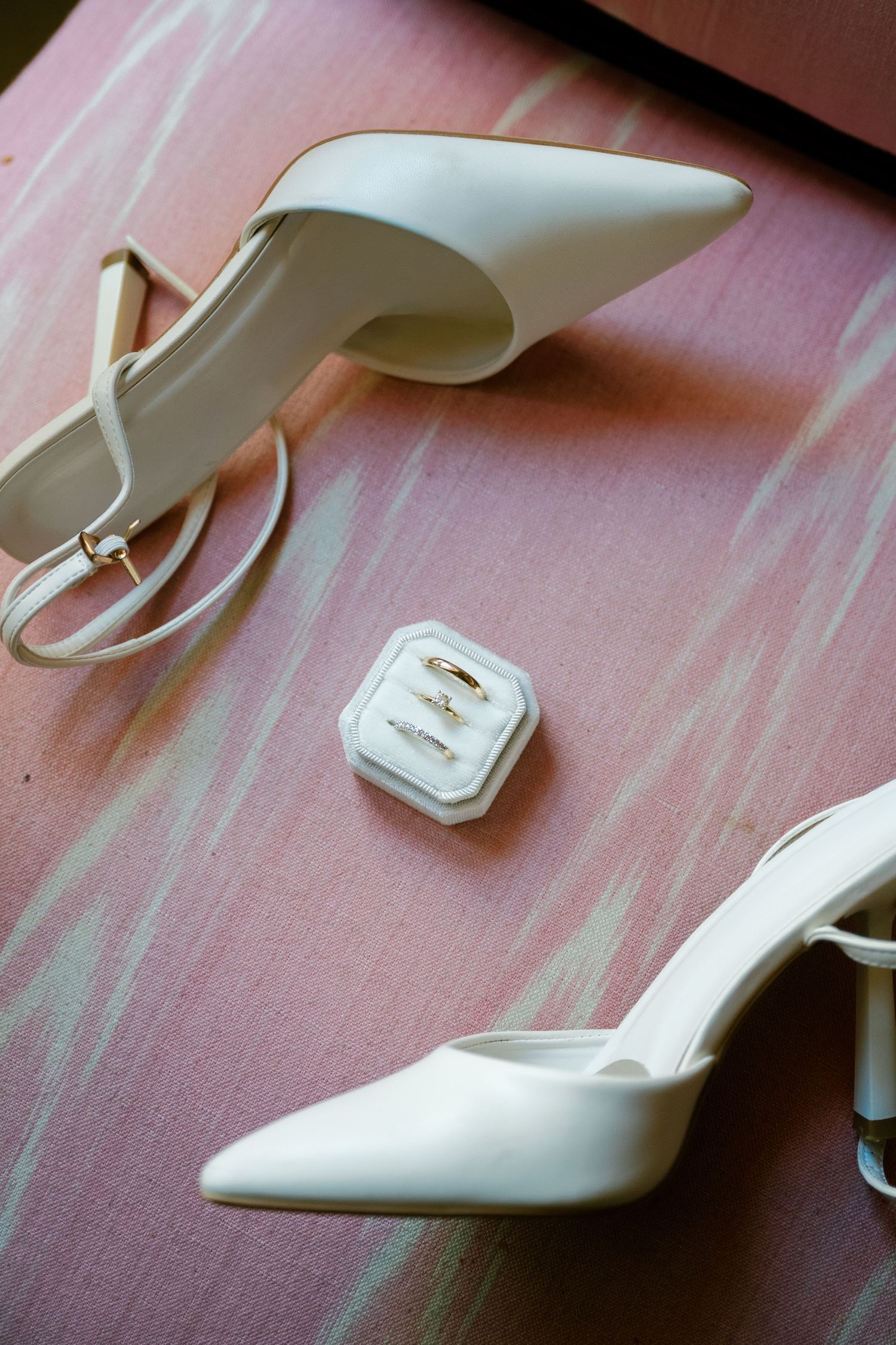 A series of white slingback high heel shoes shown at different angles on a pink wooden surface.