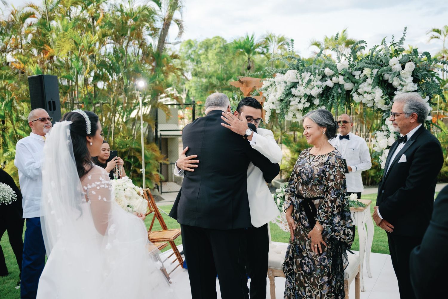 Wedding guests dancing and celebrating together at an outdoor garden reception venue.