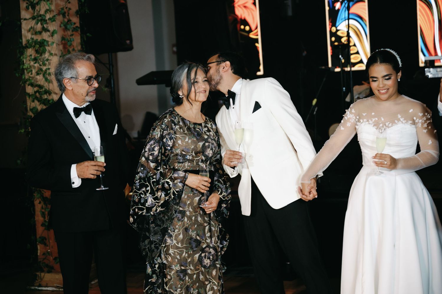 Elegantly dressed guests in formal attire dance and socialize at an upscale evening event.