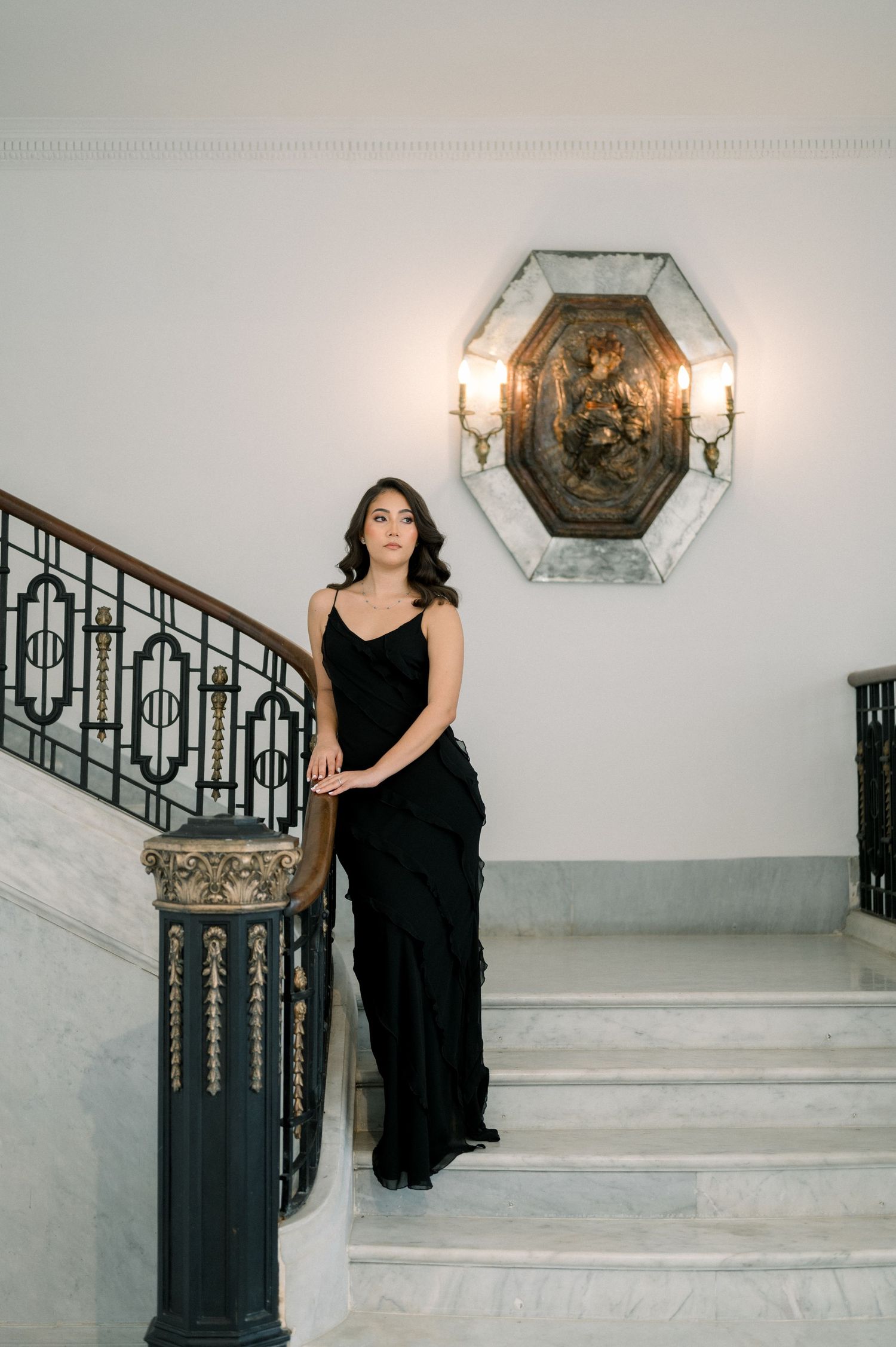 A sequence of photos showing a person in a black dress descending elegant white marble stairs with ornate railings.