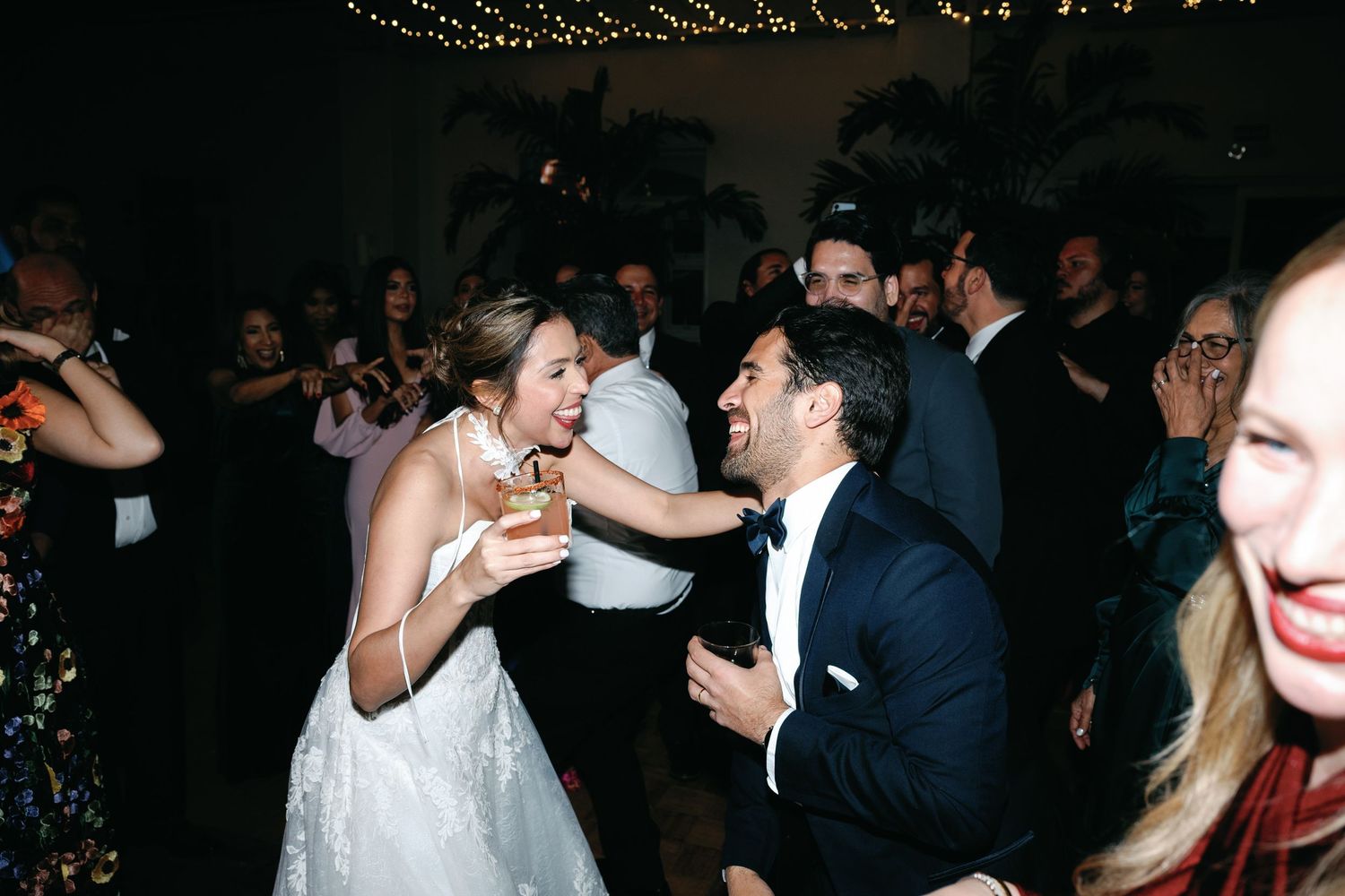 Wedding celebration with guests laughing and enjoying drinks on the dance floor.