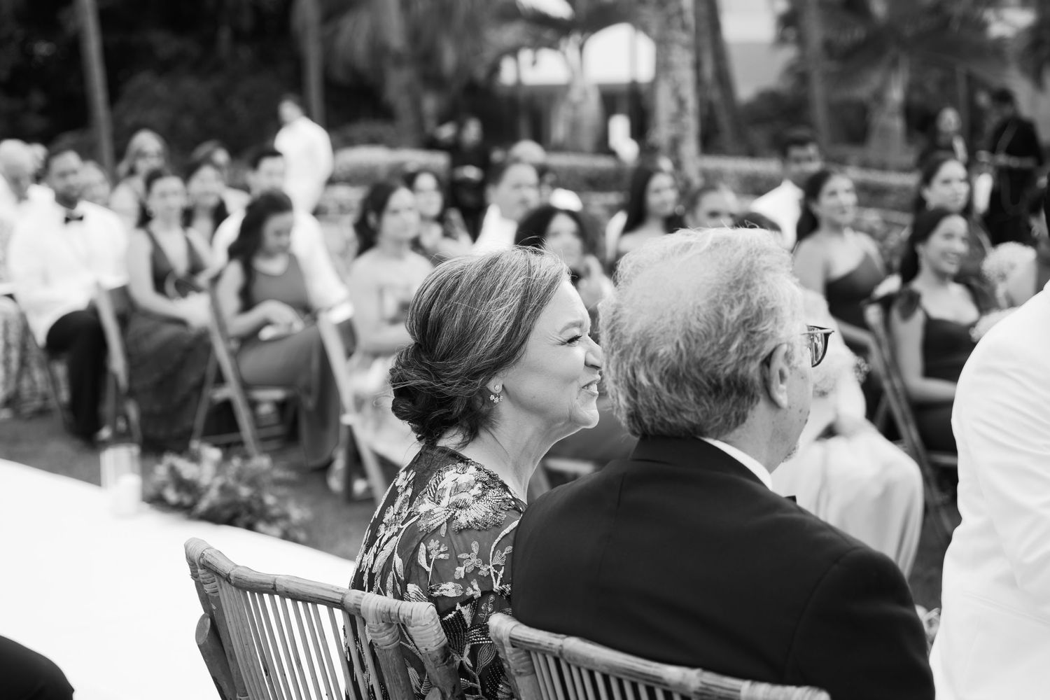 People sitting together on a park bench in black and white, viewed from behind.