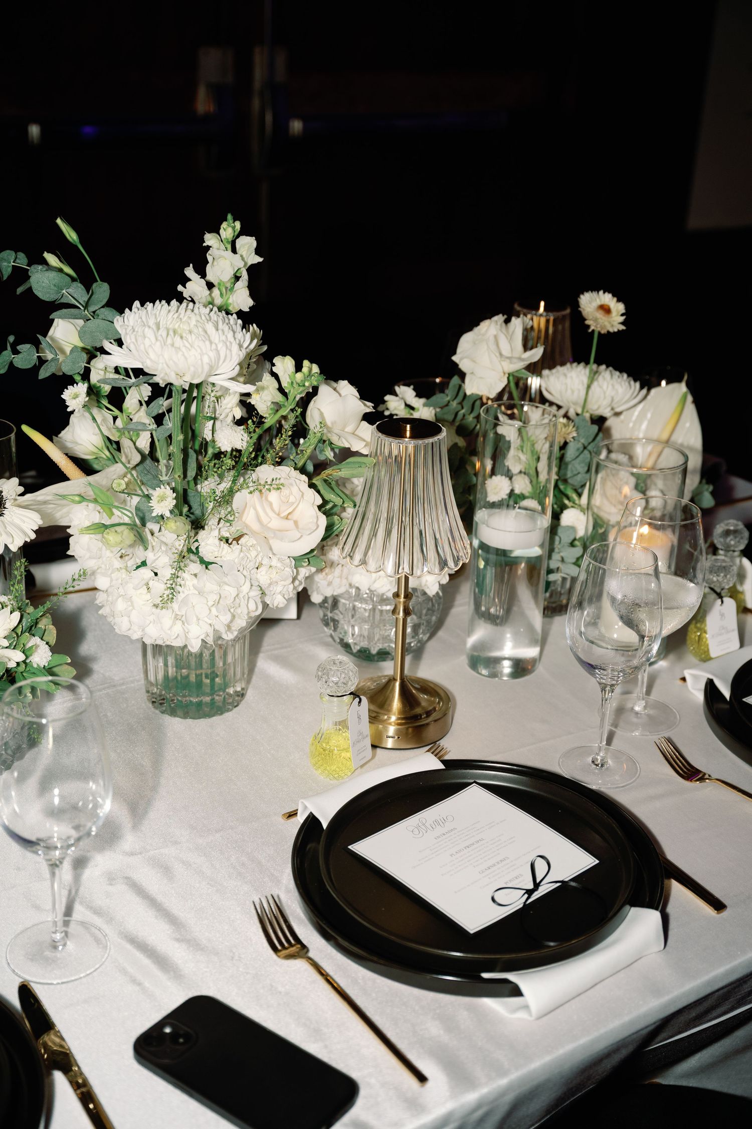 Elegant black and white table settings with crystal glassware and white floral centerpieces create a sophisticated dining atmosphere.