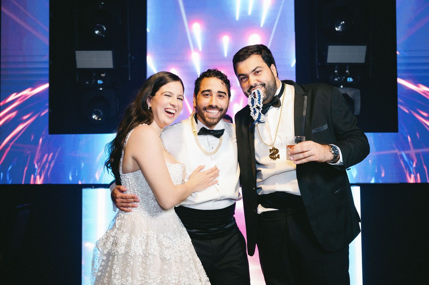 Wedding party dancing and celebrating on a blue-lit dance floor during an elegant reception.